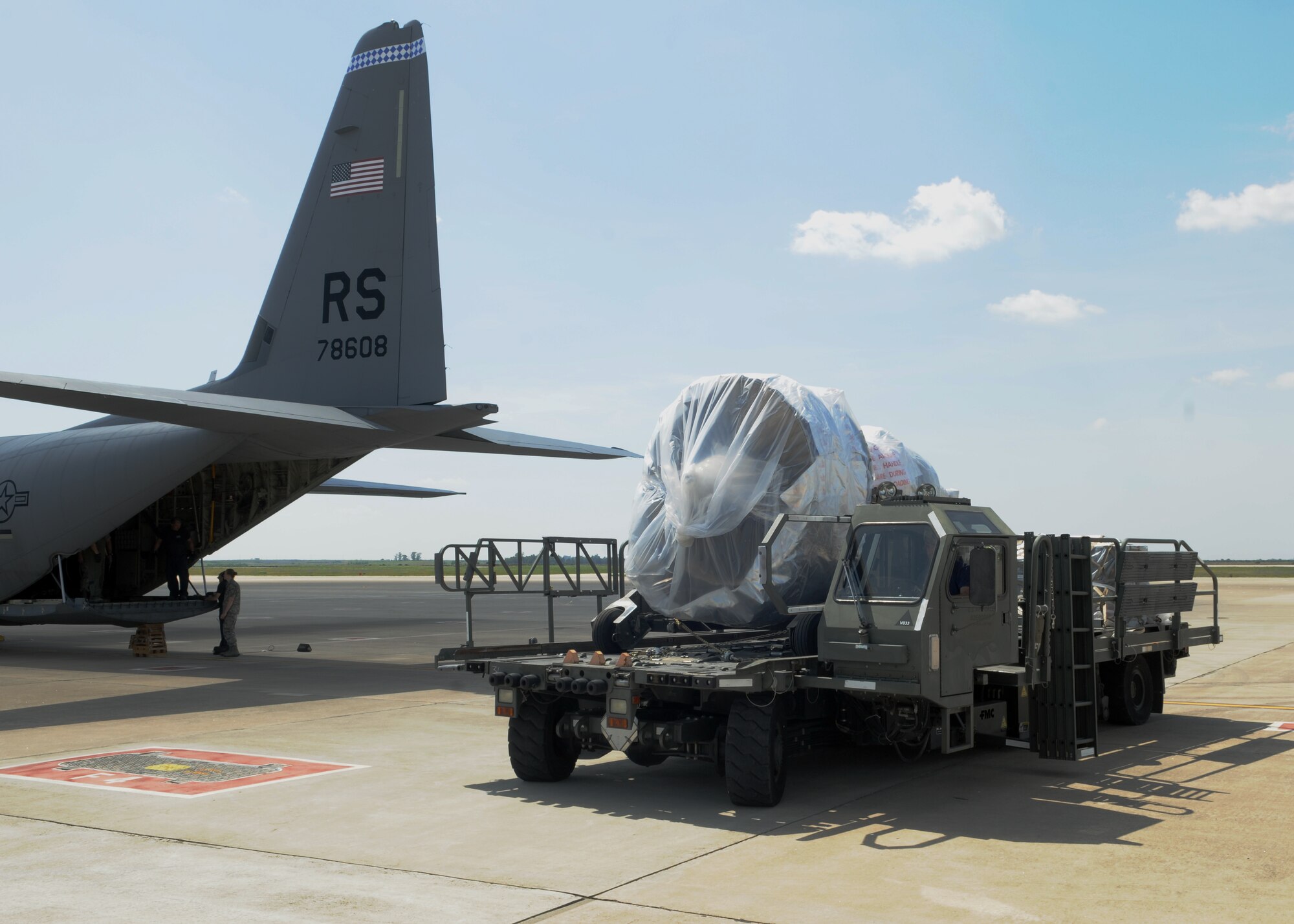 A government-service-civilian employee driving a K-loader moves a General Electric CFM-56 engine away from the C-130J Super Hercules it was delivered on April 20, 2013, in Southwest Europe. The new engine replaced the No. 4 engine on a KC-135R Stratotanker which was damaged by a bird while landing, rendering it unsafe to operate. (U.S. Air Force photo by 1st Lt. Christopher Mesnard/Released)