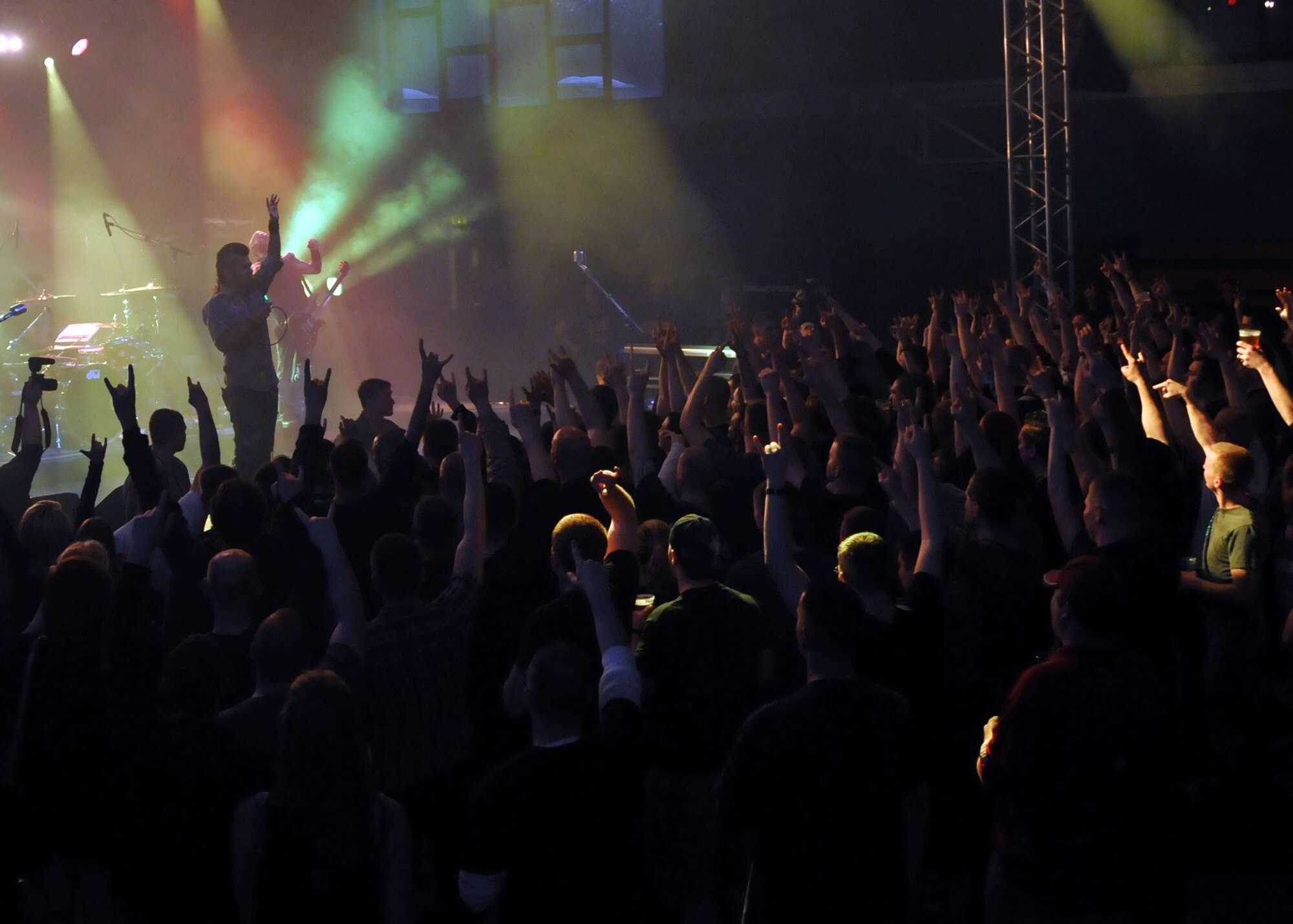 Members of Team Mildenhall raise their hands during the Drowning Pool concert May 3, 2013, at RAF Mildenhall, England. The concert was sponsored by the USO, a non-profit organization that provides programs to boost morale for service members. (U.S. Air Force photo by Airman 1st Class Kelsey Waters/Released)