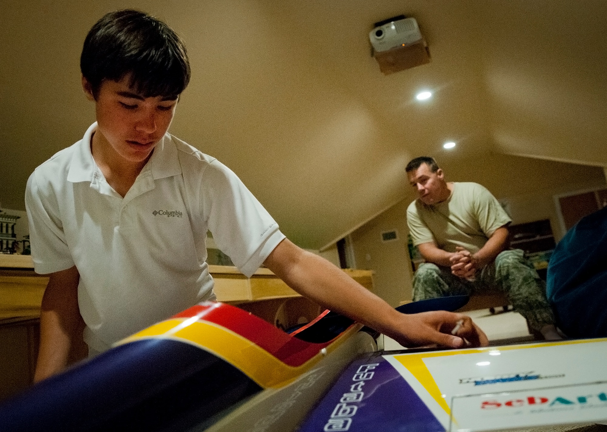 Cody Powell, the 13-year-old son of Maj. Jeff Powell, the 919th Maintenance Operations Flight commander, pieces together his competition-ready radio-controlled aircraft as his father watches in their home May 1.  Cody has won all but one of his 15 RC aircraft competitions since he and his father joined the hobby two years ago.  (U.S. Air Force photo/Tech. Sgt. Samuel King Jr.)