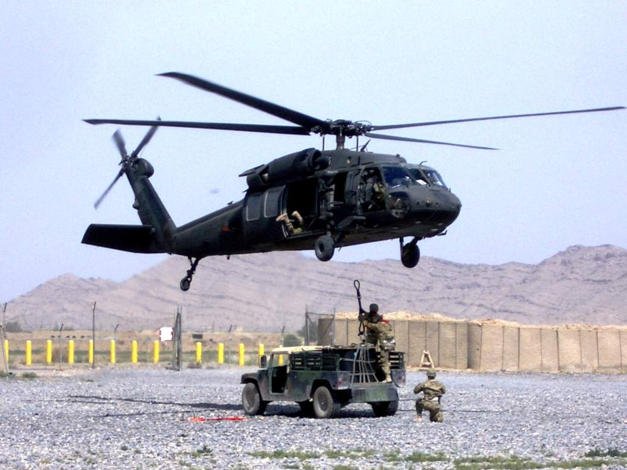 U.S. Air Force Tech. Sgt. Terry Beasley (kneeling) supervises the connection of a 1,800 pound A-22 cargo bag by U.S. Air Force Staff Sgt. Amber Varchetto and U.S. Air Force Master Sgt. George Poppe to a UH-60 Black Hawk flown by Soldiers of the 3rd Combat Aviation Brigade during a coalition-joint slingload mission at Kandahar Airfield, Afghanistan. Beasley is deployed from Moody Air Force Base, Ga. (Courtesey photo)