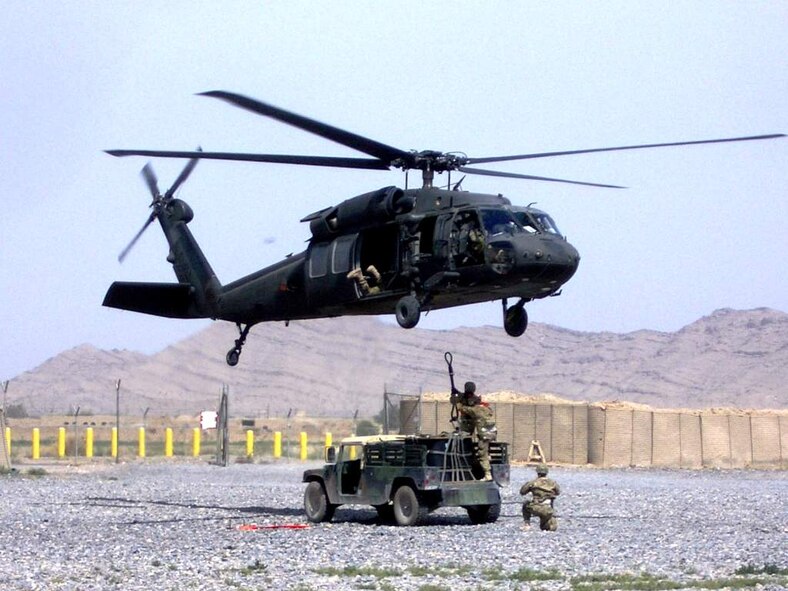 U.S. Air Force Tech. Sgt. Terry Beasley (kneeling) supervises the connection of a 1,800 pound A-22 cargo bag by U.S. Air Force Staff Sgt. Amber Varchetto and U.S. Air Force Master Sgt. George Poppe to a UH-60 Black Hawk flown by Soldiers of the 3rd Combat Aviation Brigade during a coalition-joint slingload mission at Kandahar Airfield, Afghanistan. Beasley is deployed from Moody Air Force Base, Ga. (Courtesey photo)