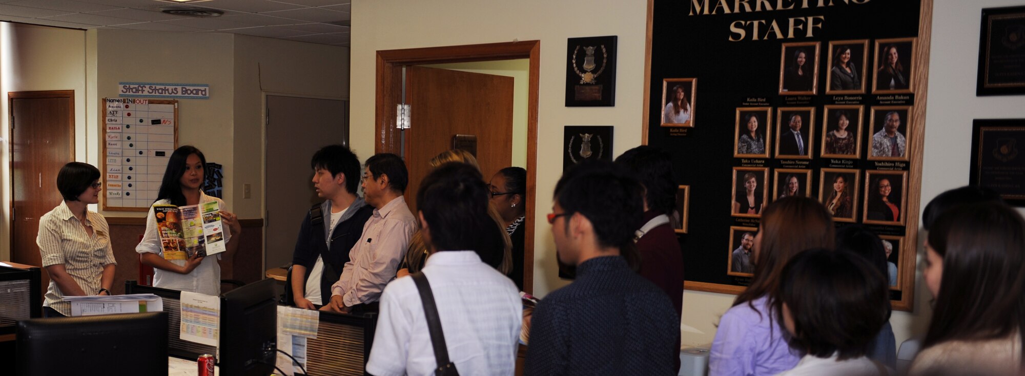 Elizabeth Enriquez (second from the left), 18th Force Support Squadron commercial sponsorship and advertising coordinator, explains the process of adding advertisement in magazines to Okinawa International University students on Kadena Air Base,  Japan, May 3, 2013. The business students visited the 18th FSS marketing section to learn how they operate and how each section is crucial to the units overall success. (U.S. Air Force photo by Airman 1st Class Keith A. James/Released)