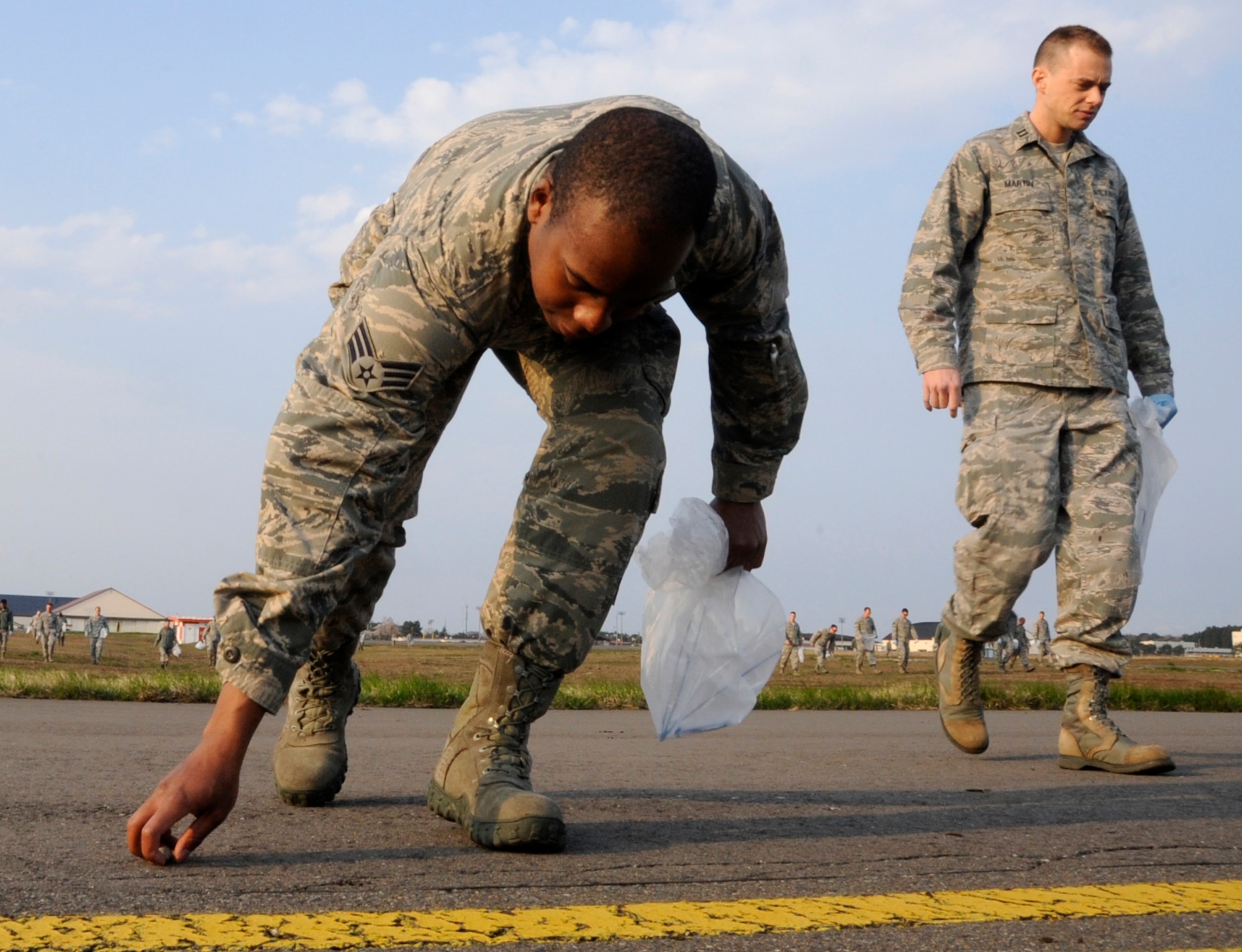 Airmen clean up foreign debris during the annual Foreign Object Damage walk at Misawa Air Base, Japan, May 6, 2013. FOD is a hazard for any aircraft and other precision equipment. Suction caused by the air intake of jet engines can pull objects into the aircraft intake and damage the engine. (U.S. Air Force photo by Airman 1st Class Kaleb Snay)