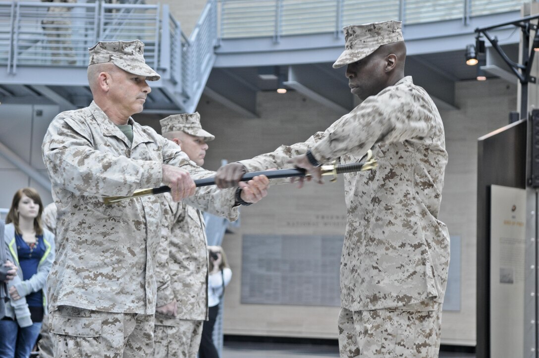 In a relief and appointment ceremony held May 7, 2013, at the National Museum of the Marine Corps, Col. Willard Buhl, commanding officer of Wounded Warrior Regiment, left, passes the ceremonial sword to Sgt. Maj. Michael Mack, the regiment’s new sergeant major, as Sgt. Maj. Joseph VanFonda, outgoing sergeant major, center, looks on. 