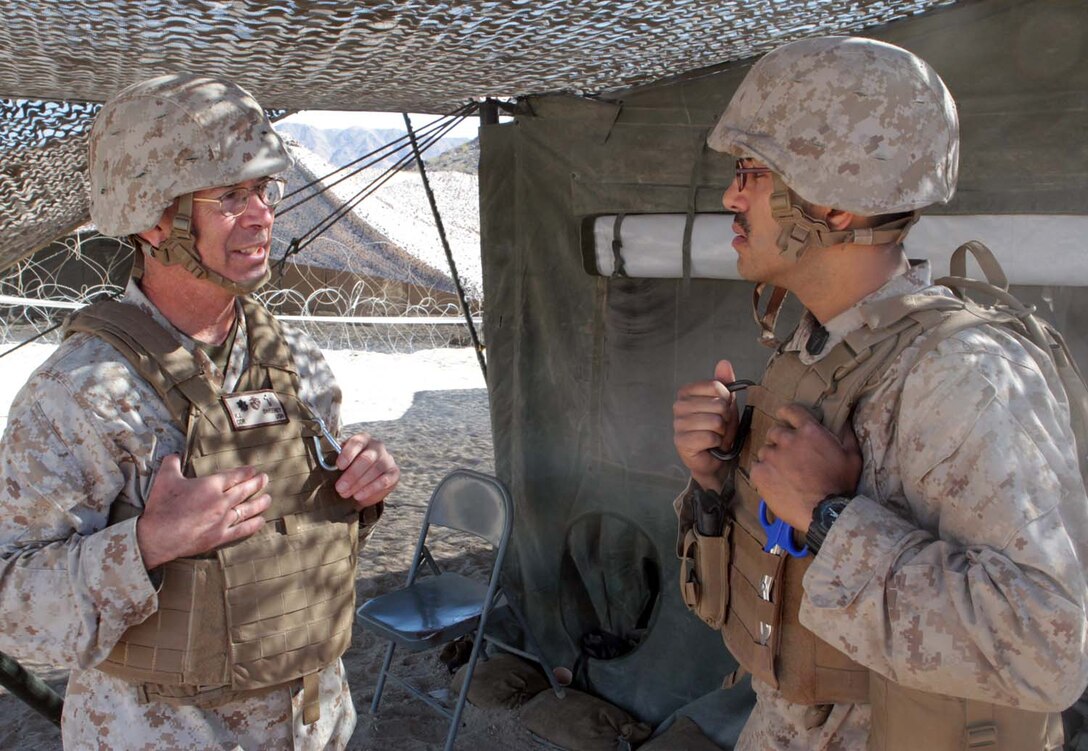 Commander Kevin J. Sweeney, the 1st Marine Division deputy chaplain, and Petty Officer 2nd Class Julio C. Trujillo, a corpsman serving with Headquarters Battalion, 1st Marine Division, chat during Exercise Desert Scimitar here, May 3, 2013. Sweeney, a 55-year-old native of Newport Beach, Calif., accompanied 1st Marine Division to the field for two weeks to provide spiritual support to more than 600 Marines and sailors. Trujillo, a 26-year-old native of Torrance, Calif., took advantage of the opportunity to talk with Sweeney.(U.S. Marine Corps photo by Sgt. Jacob H. Harrer)