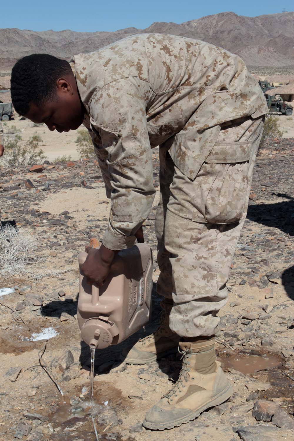 Sergeant Jevin U. Rainey, a field radio operator serving with Headquarters Battalion, 1st Marine Division, pours water to dissolve salt during Exercise Desert Scimitar here, May 2, 2013. Rainey, a 27-year-old native of Schenectady, N.Y., added salt to the soil to increase its conductivity, strengthening the grounding for nearby antennas. Proper grounding increases the range and clarity of radio transmissions. (U.S. Marine Corps photo by Sgt. Jacob H. Harrer)