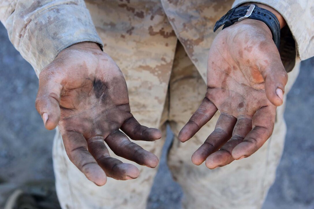 Corporal Diego Castaneda, a motor transportation maintenance chief serving with Golf Battery, 2nd Battalion, 11th Marine Regiment, holds out his hands after working on the engine of a 7-ton truck during Exercise Desert Scimitar, a combined-arms, live-fire training exercise here, May 3, 2013. Castaneda, a native of Gibbon, Neb., is the only mechanic in the battery and is in charge of keeping more than 40 vehicles properly maintained and running. Captain William Turner, the commanding officer of Golf Battery, said thanks to Castaneda's devotion and hard work, the battery is one of the few in 11th Marines that can commute to and from the Combat Center without vehicles breaking down.