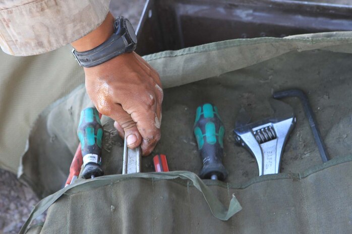 Corporal Diego Castaneda, a motor transportation maintenance chief serving with Golf Battery, 2nd Battalion, 11th Marine Regiment, grabs a wrench from his tool kit before working on a 7-ton truck during Exercise Desert Scimitar, a combined-arms, live-fire training exercise here, May 3, 2013. Castaneda, a native of Gibbon, Neb., is the only mechanic in the battery and is in charge of keeping more than 40 vehicles properly maintained and running. Captain William Turner, the commanding officer of Golf Battery, said thanks to Castaneda's devotion and hard work, the battery is one of the few in 11th Marines that can commute to and from the Combat Center without vehicles breaking down.