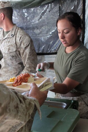 Sergeant Letty Y. Vazquez, a food service specialist serving with Combat Logistics Regiment 17, serves dinner to Marines with 1st Marine Division during Exercise Desert Scimitar here, May 1, 2013. Vazquez, a 25-year-old native of Bayamon, Puerto Rico, was attached to the division for nearly two weeks to prepare and serve hot meals for more than 600 Marines and sailors. Her team of food service specialists often worked more than 20 hours each day to feed the division.(U.S. Marine Corps photo by Sgt. Jacob H. Harrer)