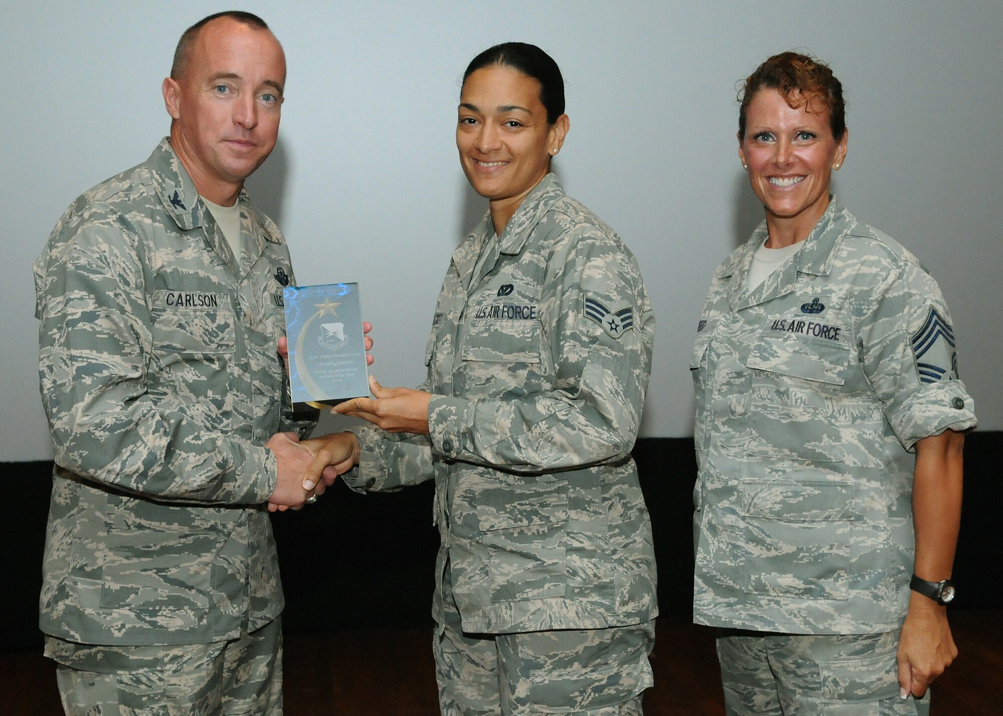 Col. Dann S. Carlson, 647th Air Base Group commander, left, and CMSgt Karen Reed, 647th Air Base Group chief, right, presents a 647th ABG Airman of the Year plaque to SrA Erika Berniercruz, 647th ABG civil engineering journeyman, during Carlson’s final commander’s call as the 647th commander, at the Memorial Theater at Joint Base Pearl Harbor Hickam, Hawaii, May 3, 2013. (Photo by David D. Underwood, Jr.)