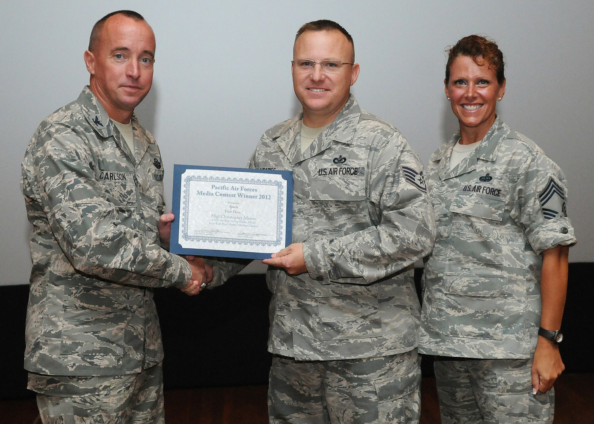 Col. Dann S. Carlson, 647th Air Base Group commander, left, and Chief Master Sgt. Karen Reed, 647th Air Base Group chief, right, present a Pacific Air Forces Media contest certificate to Staff Sgt. Christopher Meares, 647th ABG public affairs journalist, during Carlson’s final commander’s call as the 647th ABG commander, at the Memorial Theater at Joint Base Pearl Harbor Hickam, Hawaii, May 3, 2013. (Photo by David D. Underwood, Jr.)