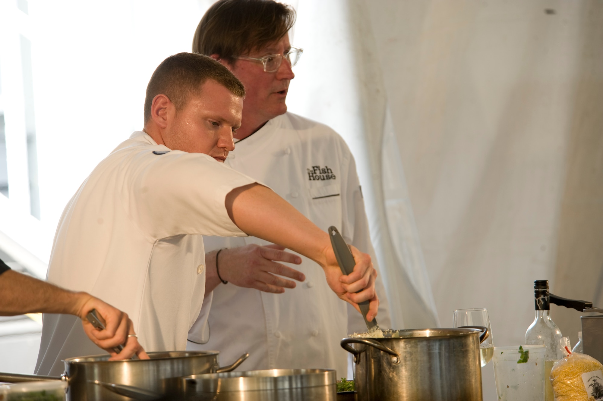 Airman 1st Class Eric Rydecki, a food service specialist with 1st Special Operations Force Support Squadron, helps Jim Shirley, a local chef and restaurateur, in a cooking demonstration at the Navarre Beach Chamber of Commerce’s ‘Taste of Navarre Seafood’ in the Navarre Park at Navarre, Fla., April 28.  Rydecki participated in the first half of the cooking demonstrations at the event, which included using fresh sea food caught in the Gulf of Mexico.  (U.S. Air Force Photo by Airman 1st Class Benjamin Kim)