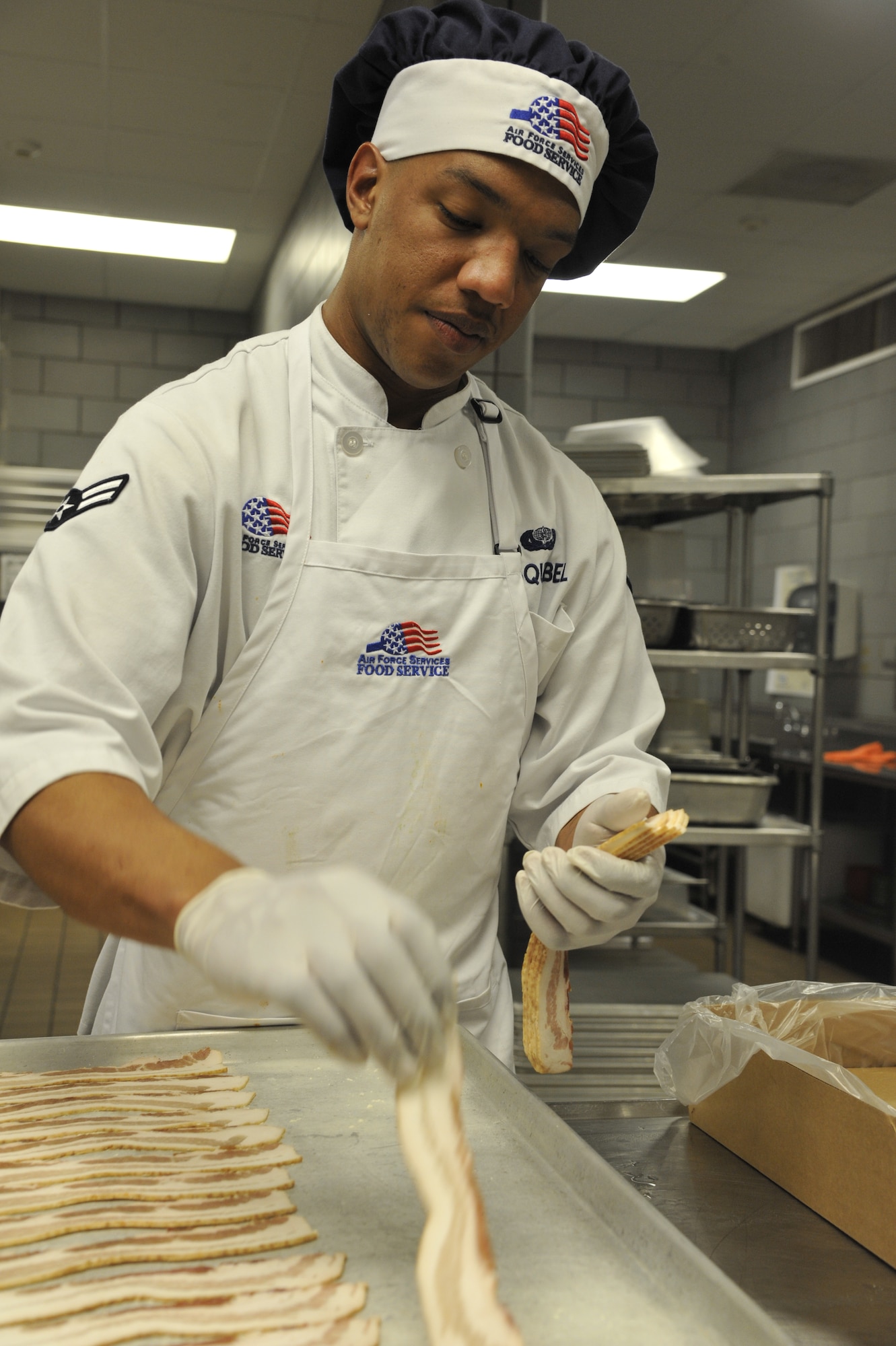Airman 1st Class Curtis Esquibel, 509th Force Support Squadron services apprentice, prepares bacon at the Ozark Inn on Whiteman Air Force Base, Mo. April 15, 2013. Prepping food early helps dining facility staff members stay on schedule with meal services throughout each shift. (U.S. Air Force photo by Airman 1st Class Keenan Berry/Released)