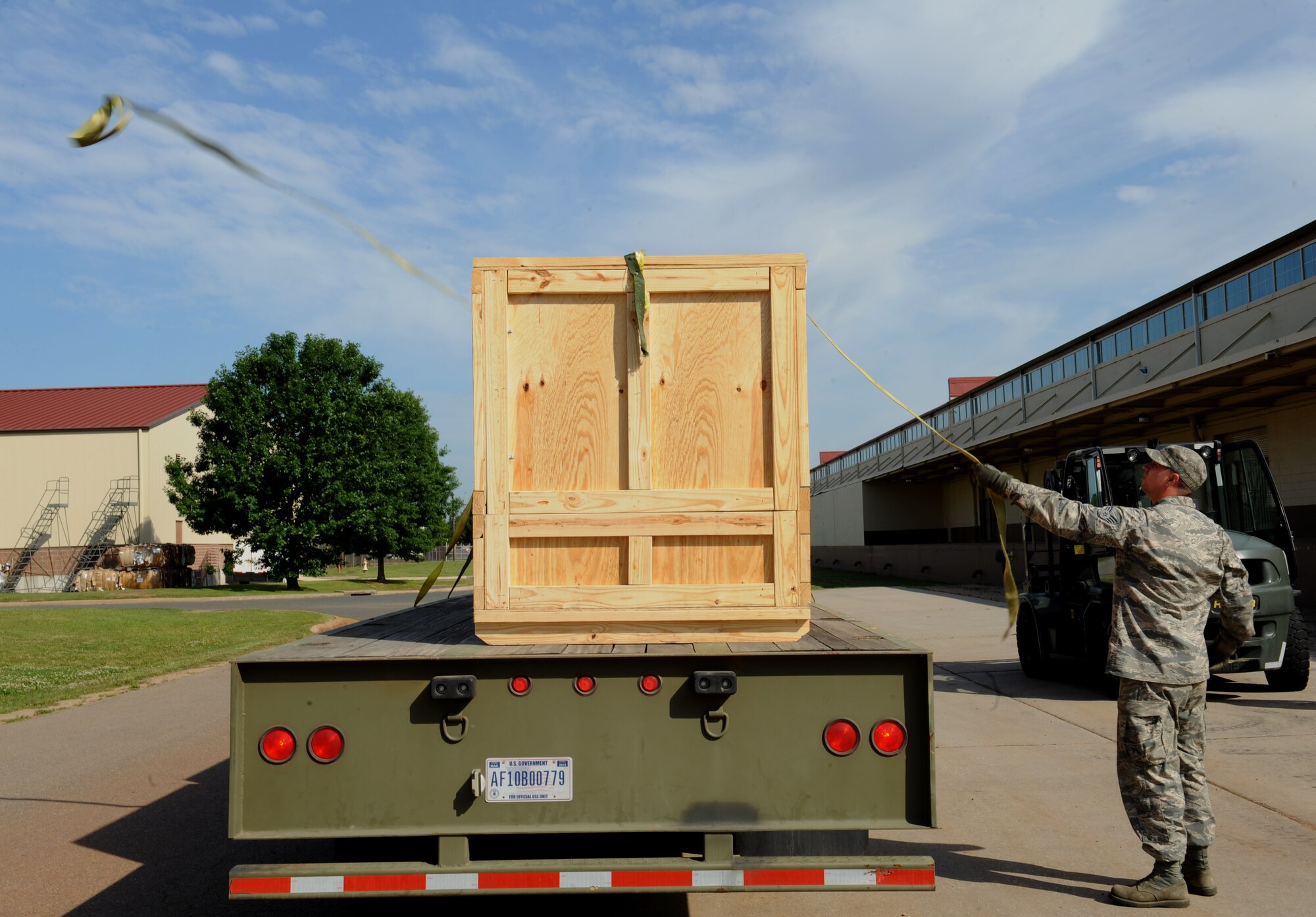 Senior Airman Jeff Dean, 2nd Logistics Readiness Squadron vehicle operator, throws a tow strap over a crate on Barksdale Air Force Base, La., May 7, 2013. Vehicle operators must ensure cargo is properly secured to the vehicle before transporting it to its destination. (U.S. Air Force photo/Airman 1st Class Benjamin Gonsier)

