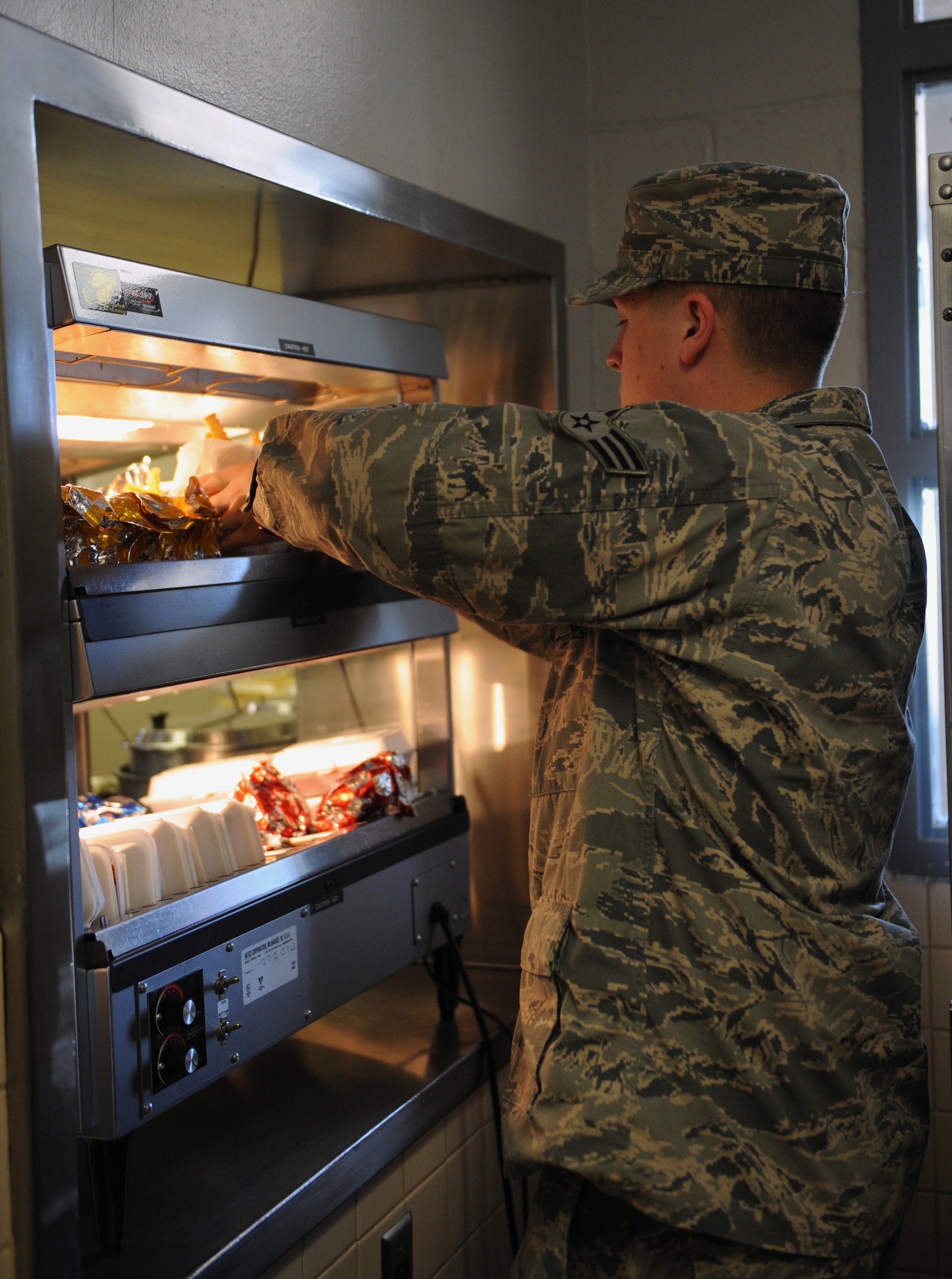 Senior Airman David Goloven, 2nd Force Support Squadron food services, places food items on a heated shelf at the Touch-N-Go flight kitchen on Barksdale Air Force Base, La., May 6, 2013. The flight kitchen gives Airmen and aircrew on the flightline a chance to grab food when the mission makes it difficult to take a full lunch. (U.S. Air Force photo/Airman 1st Class Benjamin Gonsier)
