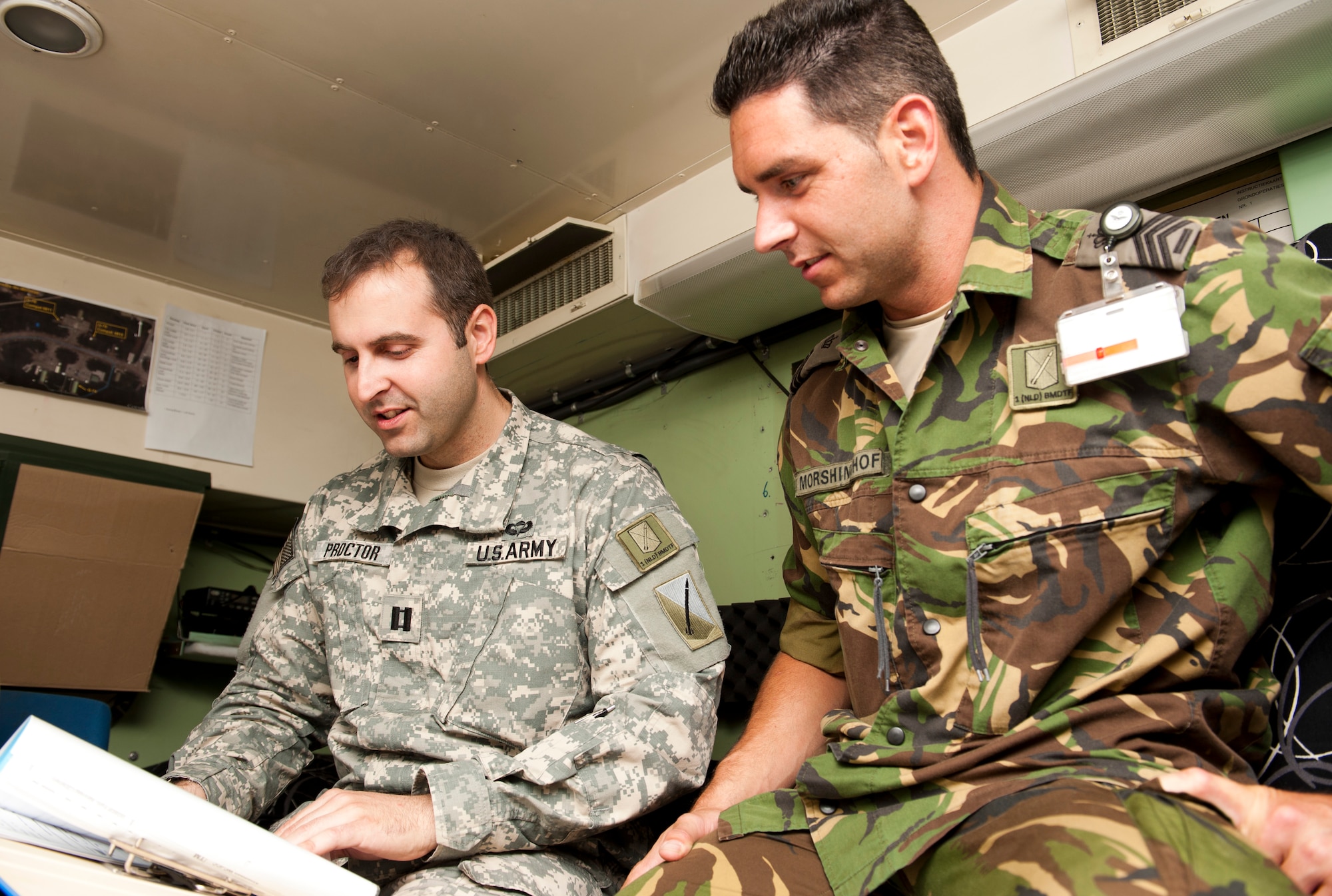 U.S. Army Capt. Adam Proctor, 1st Netherlands Ballistic Missile Defense Task Force Dutch missile systems tactical director, and Dutch army Sgt. 1st Class Rob Morsinkhof, 1st NBMDTF soldier, look over regulations April 26, 2013, at Incirlik Air Base, Turkey. Proctor is a U.S. Army soldier currently deployed to Turkey with the Dutch military as a foreign exchange officer. (U.S. Air Force photo by Senior Airman Daniel Phelps/Released)