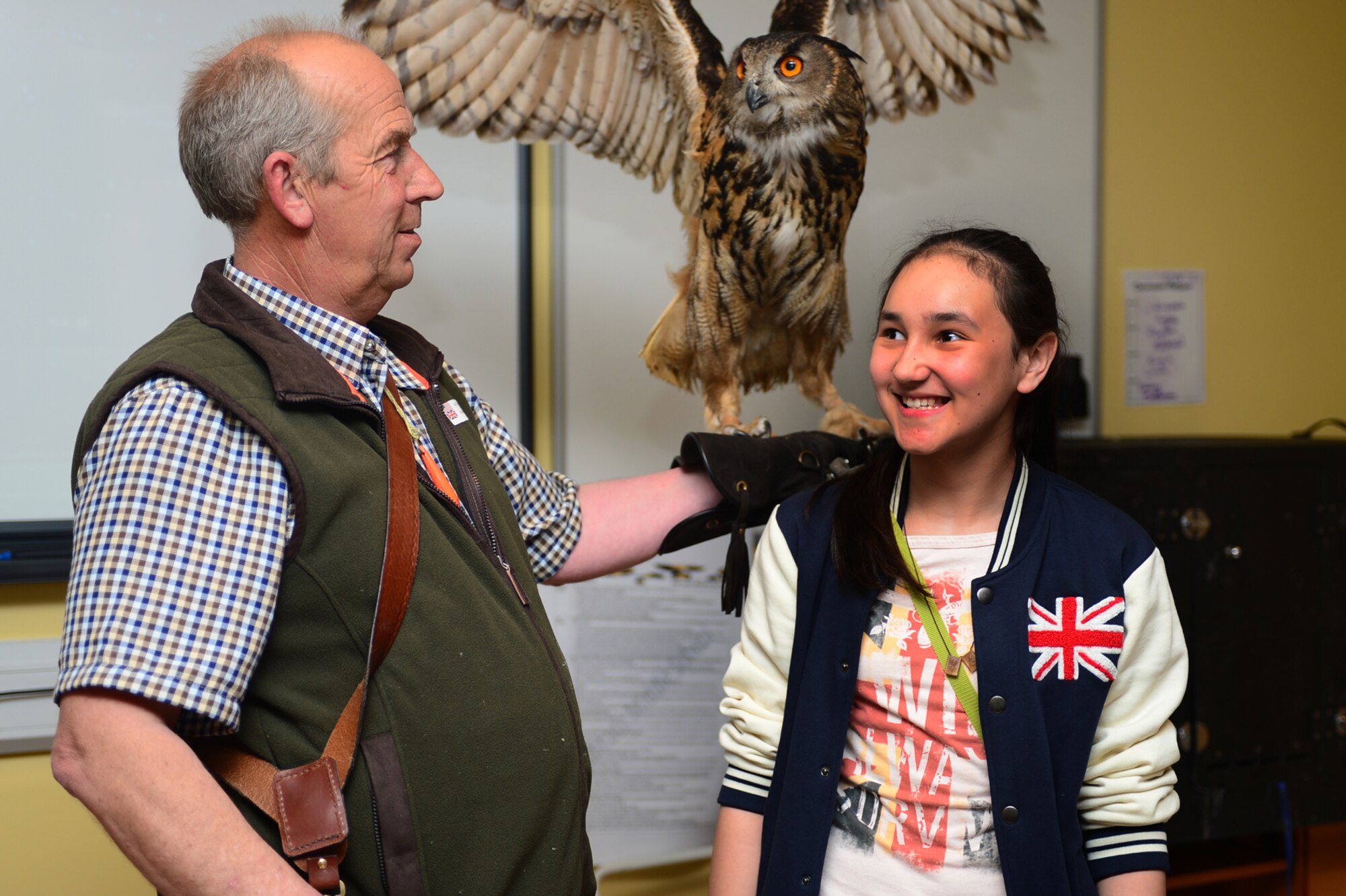 ROYAL AIR FORCE FELTWELL, England -- Keith Mutton, Phoenix Bird Control falconer, shows off Twinkle, a 25-year-old eagle owl, to seventh-grader Kiana Young, daughter of Master Sgt. John Young, 48th Equipment Maintenance Squadron aerospace ground equipment flight chief, during the Lakenheath Middle School U.K. Day May 3, 2013.  U.K. Day is an annual event designed to educate children on U.K. customs, history and heritage and to foster a relationship with the host nation. (U.S. Air Force photo by Airman 1st Class Dana J. Butler)