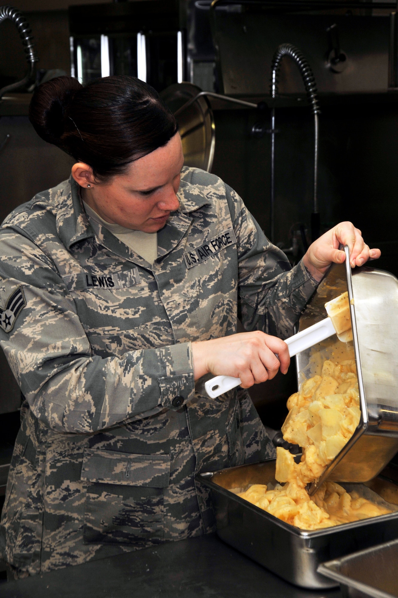 U.S. Air Force Senior Airman Catherine Lewis, 35th Force Support Squadron food services shift leader, combines two pans of potatoes au gratin at Misawa Air Base, Japan, April 18, 2013. The Grissom Dining Facility here can serve more than 600 people daily over four different meals. (U.S. Air Force photo by Airman 1st Class Zachary Kee)