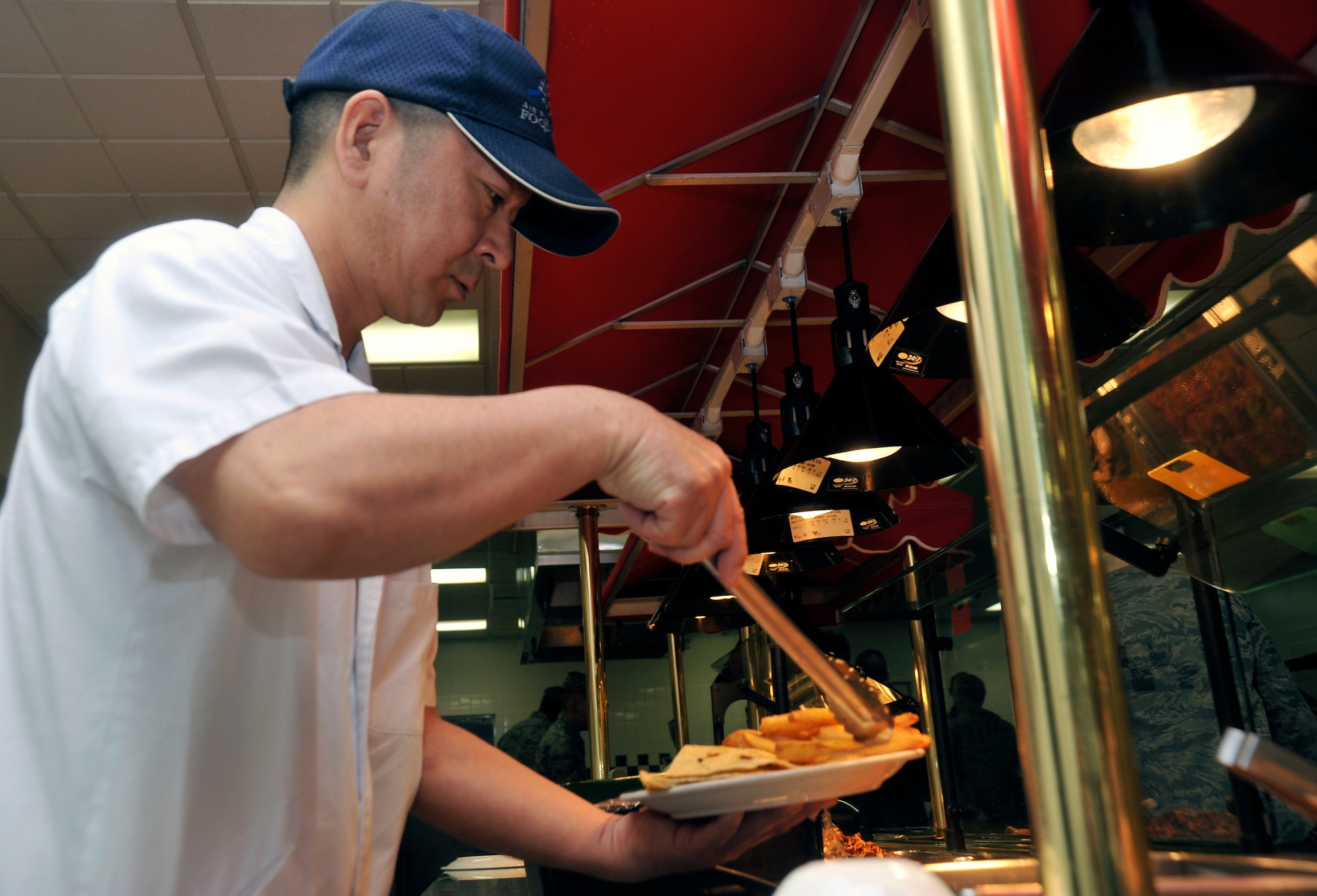 Koji Kanazawa, 35th Force Support Squadron food services contractor, prepares an Airman’s plate at Misawa Air Base, Japan, April, 18, 2013. With the help of Japanese contractors at the Grissom Dining Facility, food services Airmen can serve customers through the line faster and focus on other tasks that need to be completed. (U.S. Air Force photo by Airman 1st Class Zachary Kee)