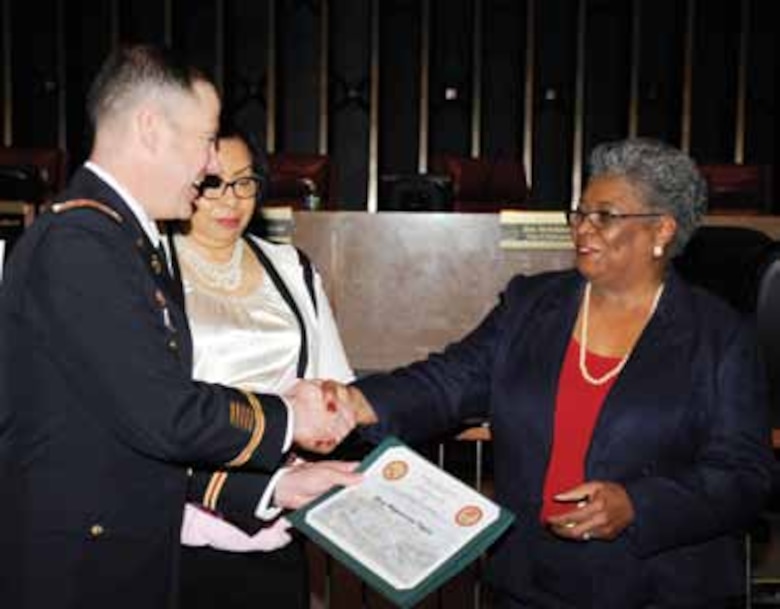 Assisted by Special Emphasis Committee Chair Karen Brady (center), Deputy Commander Lt. Col. Dave Patton, left, presents a certificate of appreciation to Madeleine Taylor.