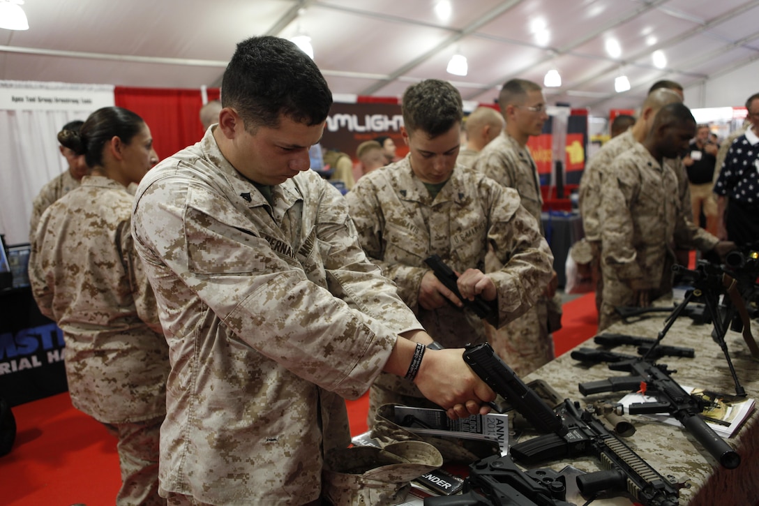 Cpl. Wally Hernandez and Cpl. Chris Davis, electronic intelligence intercept operators with 2nd Radio Battalion, handle a hand guns at a weapons display at Marine South Military Expedition aboard Marine Corps Base Camp Lejeune April 10. Marine South Military Exposition gave Marines the ability to give feedback about products they use.
