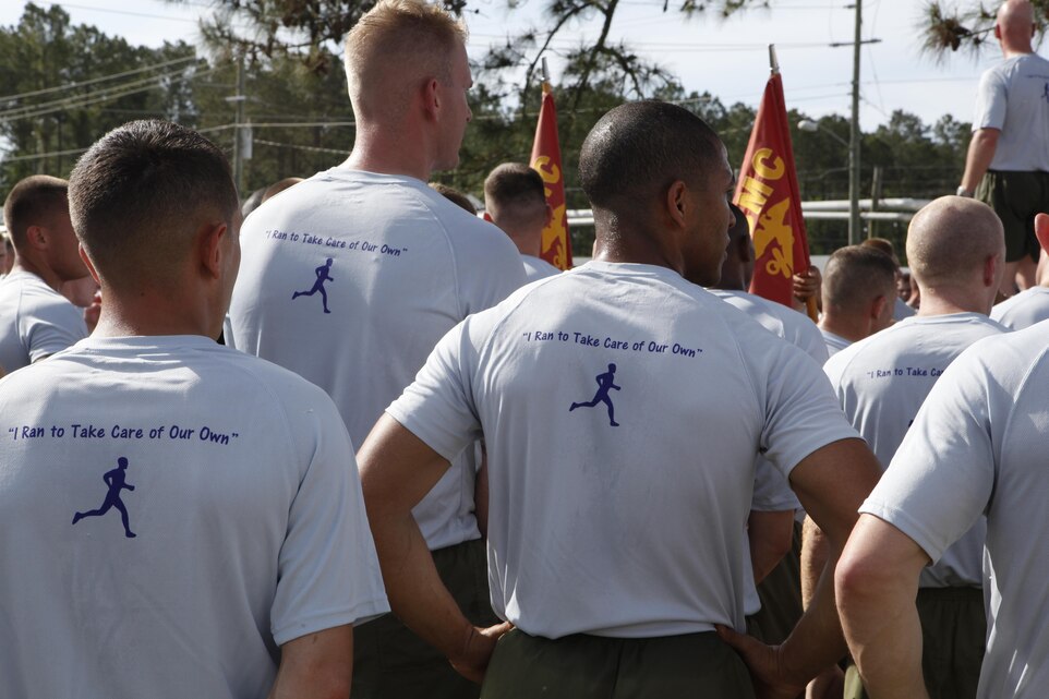 Marines wearing T-Shirts they bought to support the Navy Marine Corps Relief Society listen to a presentation at the conclusion of a three-mile fun run April 18. The shirts feature the Navy Marine Corps Relief Society’s logo on the front and the silhouette of a man running with the words “I ran to take care of our own,” on the back.