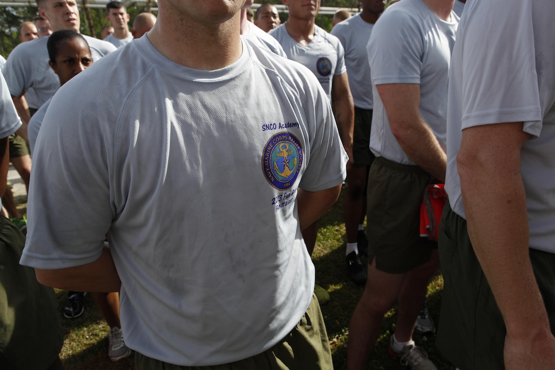 Marines wearing T-Shirts they bought to support the Navy Marine Corps Relief Society listen to a presentation at the conclusion of a three-mile fun run April 18. The shirts feature the Navy Marine Corps Relief Society’s logo on the front and the silhouette of a man running with the words “I ran to take care of our own,” on the back.