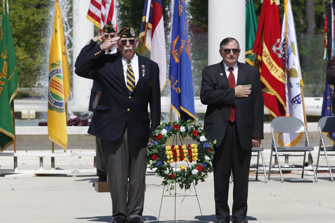 Michael Carr, president of the Jon Paranese Chapter of the Vietnam Veterans of America, salutes and Paul Buchanan, chairman of the Onslow County Board of Commissioners places his hand over his heart  during taps at Lejeune Memorial Gardens during Vietnam Recognition Day April 27. The Jon Panarese Chapter of the Vietnam Veterans of America hosted the event with the support of Marine Corps Base Camp Lejeune which provided the color guard, firing detail and a bugler.