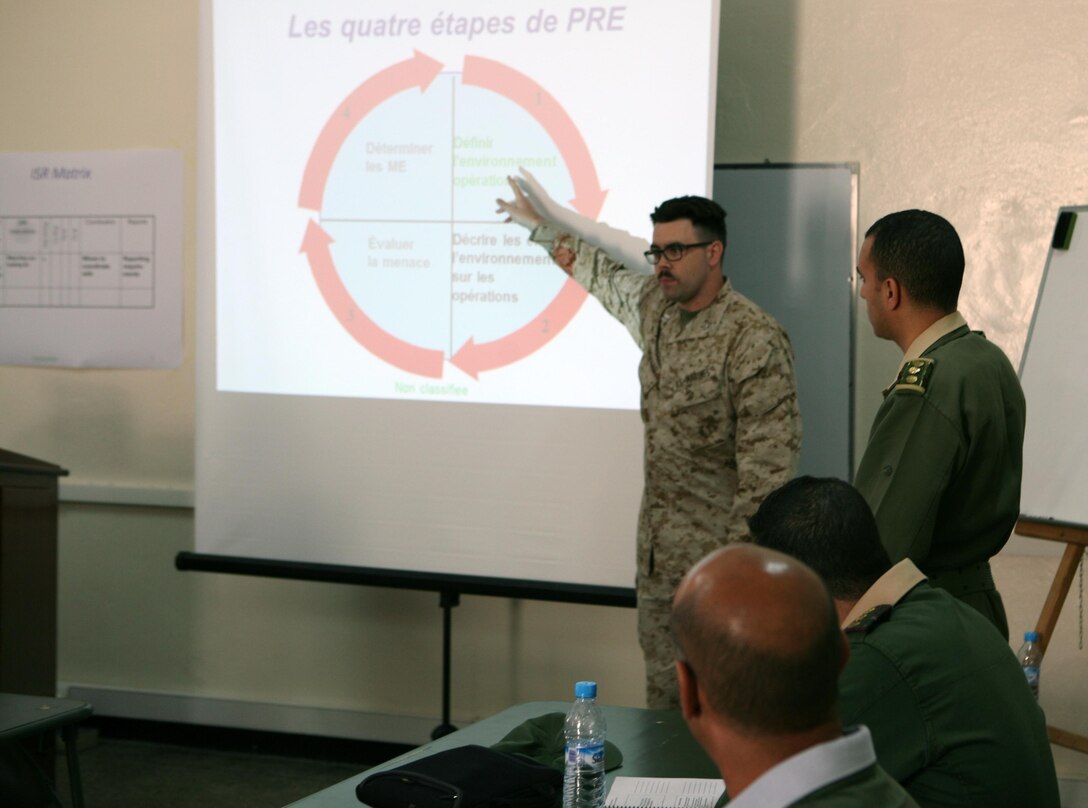 Captain Andrew Howard, an intelligence officer instructor assigned to Exercise African Lion 13, introduces “systematic approaches to terrain” during an Intelligence Capacity Building Workshop with U.S., Moroccan and German intelligence officers, April 11. Exercise African Lion is a U.S. Africa Command-scheduled, U.S. Marine Corps Forces Africa- led, joint multi-lateral exercise. The joint task force consisting of U.S. Marines, soldiers, sailors and airmen were able to conduct modified joint training for Exercise African Lion 13, demonstrating their ability to adapt to unpredicted circumstances, restore mission essential tasks, build interoperability and create friendships during the remaining days of the evolution. The logistics component will continue to exercise vigilant, safe and rapid retrograde of almost 1,200 personnel and 250 short-tons of vehicles and equipment while working with Moroccan partners and contractors to sustain the force and redeploy them back to their home stations in a timely and efficient manner.