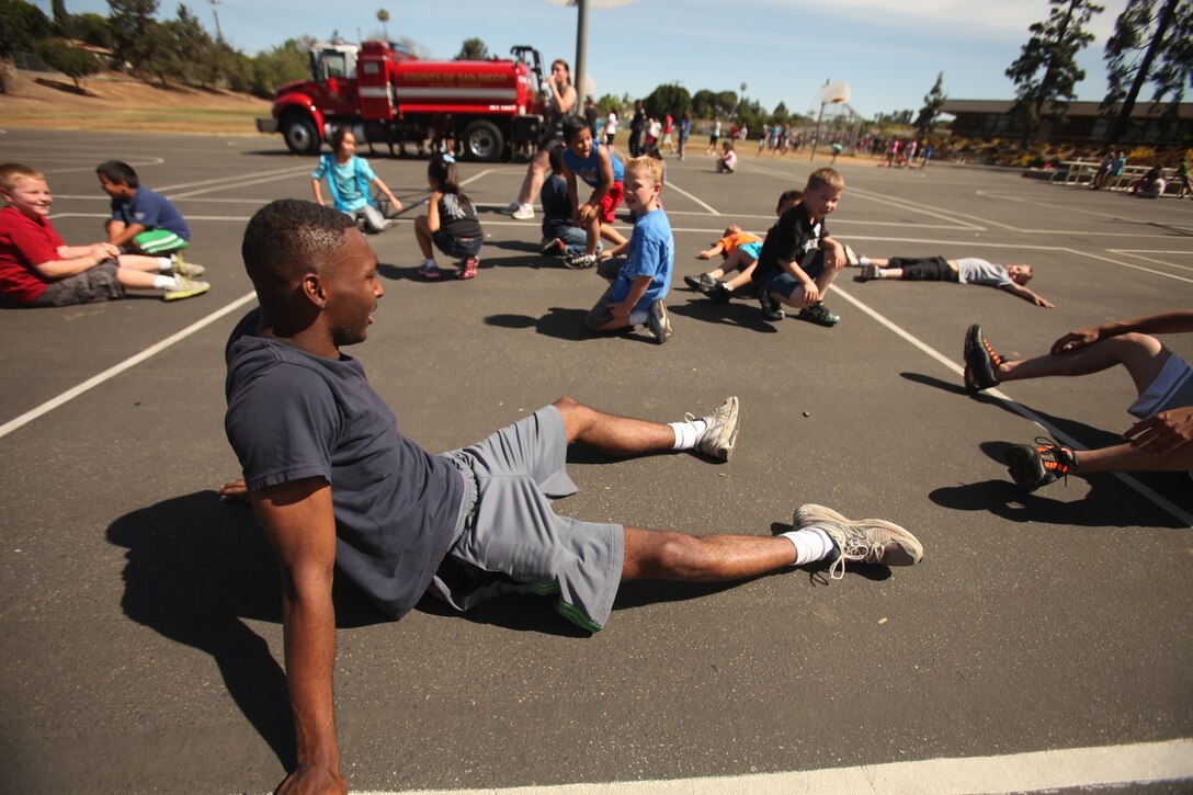 Lance Cpl. Divon Grant, an administrative specialist with Combat Logistics Regiment 17 and a native of Savannah, Ga., relaxes with several La Paloma Elementary School students after participating in the school’s jog-a-thon, May 3, 2013. Ten Marines with CLR-17 and 7th Engineer Support Battalion spent the afternoon running with students from kindergarten through sixth grade in order to motivate and make the children’s experience more memorable.