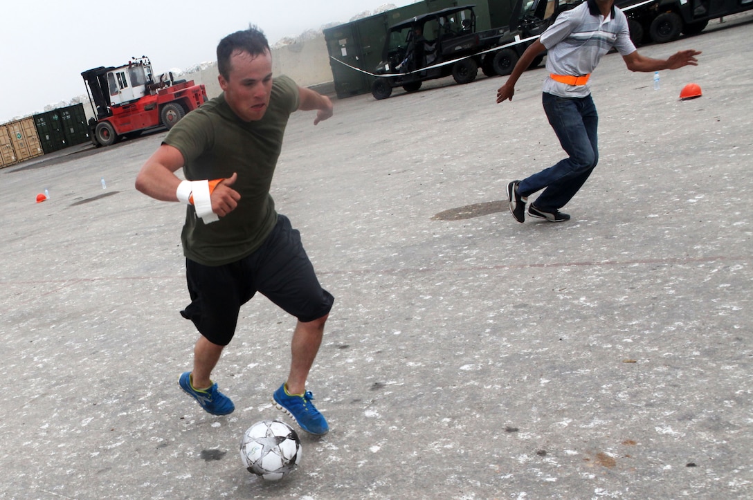 Lance Corporal Corey D. Ramos, an Abilene, Texas, native and motor transportation mechanic assigned to Exercise African Lion 13 from 4th Maintenance Battalion, 4th Marine Logistics Group, kicks a soccer ball past a Moroccan defender at the port here April 15, during a soccer game celebrating the success of a large-scale, joint port operation in preparation for the training engagement. Exercise African Lion is a U.S. Africa Command-scheduled, U.S. Marine Corps Forces Africa- led, joint multi-lateral exercise. In April, the joint task force consisting of U.S. Marines, soldiers, sailors and airmen were able to conduct modified, joint training for Exercise African Lion 13, demonstrating their ability to adapt to unpredicted circumstances, restore mission essential tasks, build interoperability and create friendships during the remaining days of the evolution. The logistics component continue d to exercise vigilant, safe and rapid retrograde of almost 1,200 personnel and 250 short-tons of vehicles and equipment while working with Moroccan partners and contractors to sustain the force and redeploy them back to their home stations in a timely and efficient manner. 