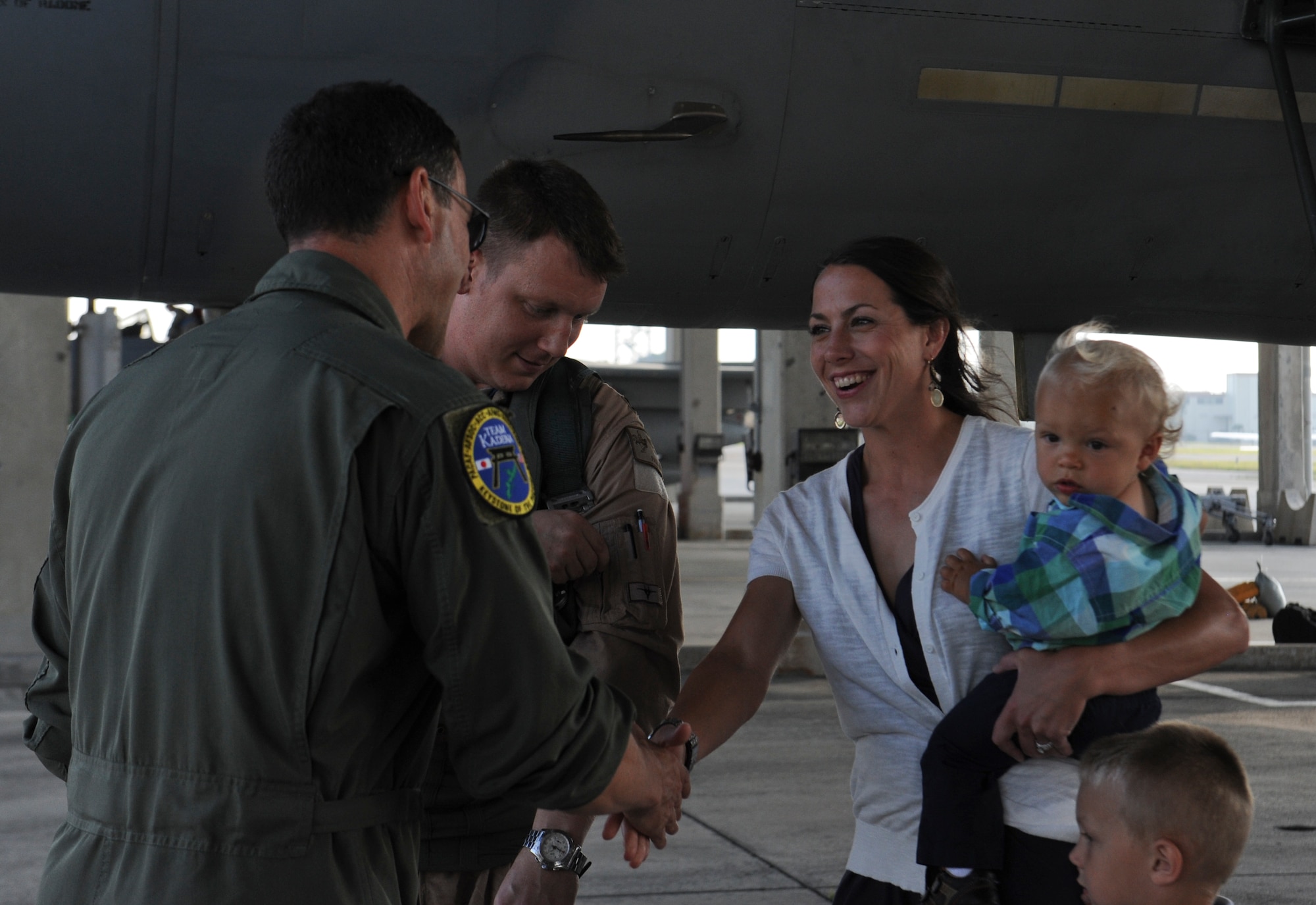U.S. Air Force Brig. Gen. Matt Molloy, 18th Wing commander, greets Capt. Paul Baker, 67th Fighter Squadron F-15 Eagle pilot, and his family on Kadena Air Base, Japan, May 8, 2013, after he returned from an eight-month deployment. Family members and friends wore an article of red clothing to show support and pride for the squadron during the homecoming. (U.S. Air Force photo by Airman 1st Class Malia Jenkins/Released)