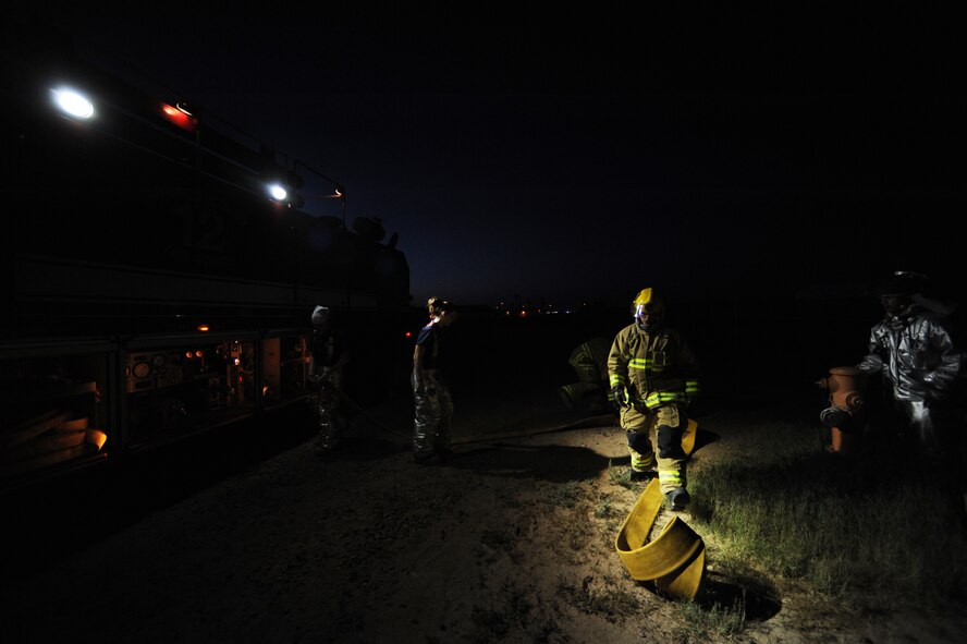 Firefighters from the 56th Civil Engineer Squadron prepare a hose to refill a P-12 Stryker fire truck April 15, 2013, during a night fire exercise at Luke Air Force Base, Ariz. The P-12 Stryker can deliver up to 1,950 gallons of water and foam mixed agent per minute to extinguish petroleum fires. (U.S. Air Force photo/Airman 1st Class Pedro Mota)