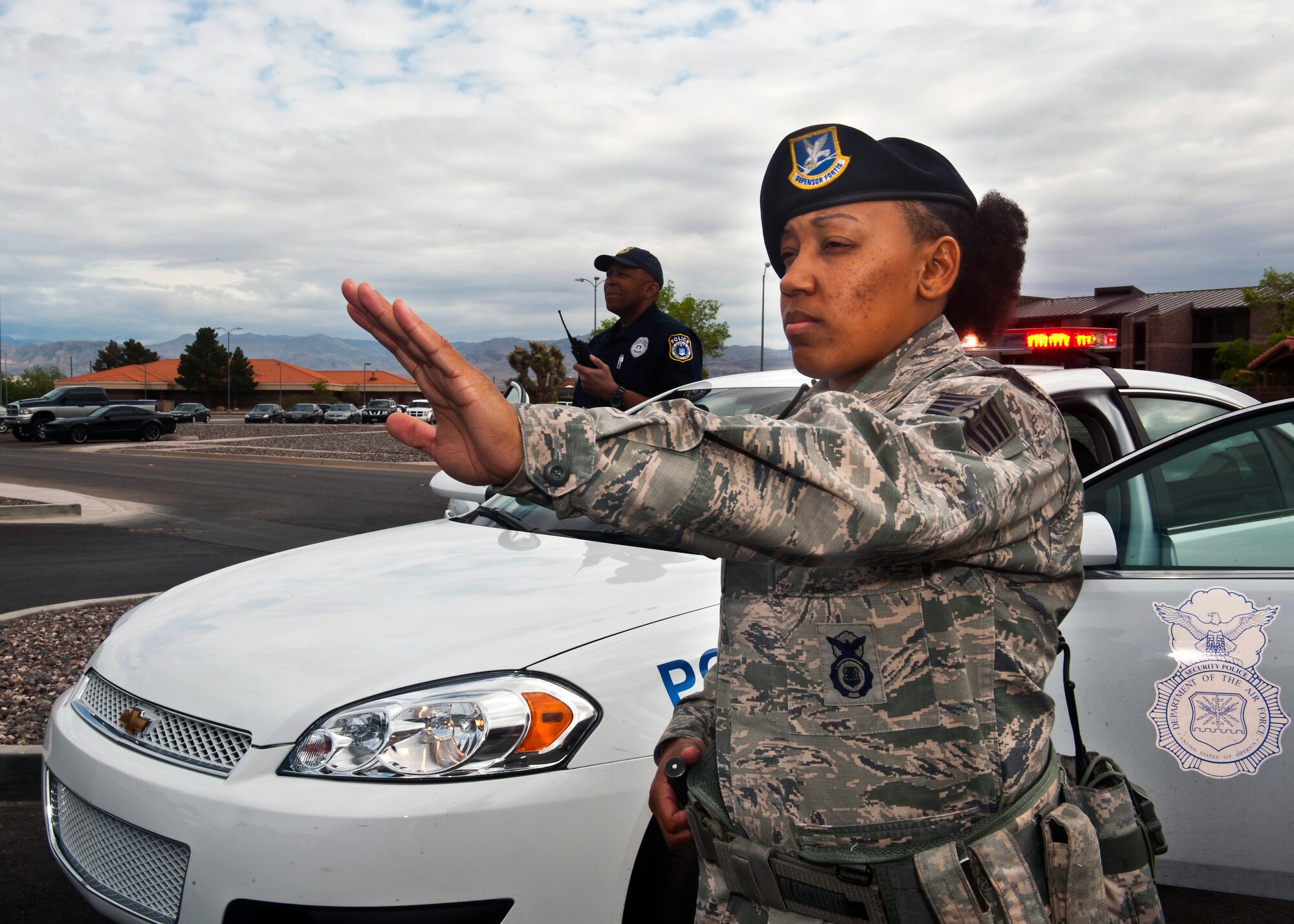 Staff Sgt. Yvonne Burnett and Officer Bobby Ward, 99th Security Forces Squadron patrolmen, stop traffic May 8, 2013, at Nellis Air Force Base, Nev. Nellis AFB will be conducting a base-wide exercise May 16 beginning at 4 p.m. during which individuals remaining on base should expect significant traffic delays and ID checks as a result of a heightened security posture and the possible implementation of a barrier plan. (U.S. Air Force photo/Senior Airman Brett Clashman)