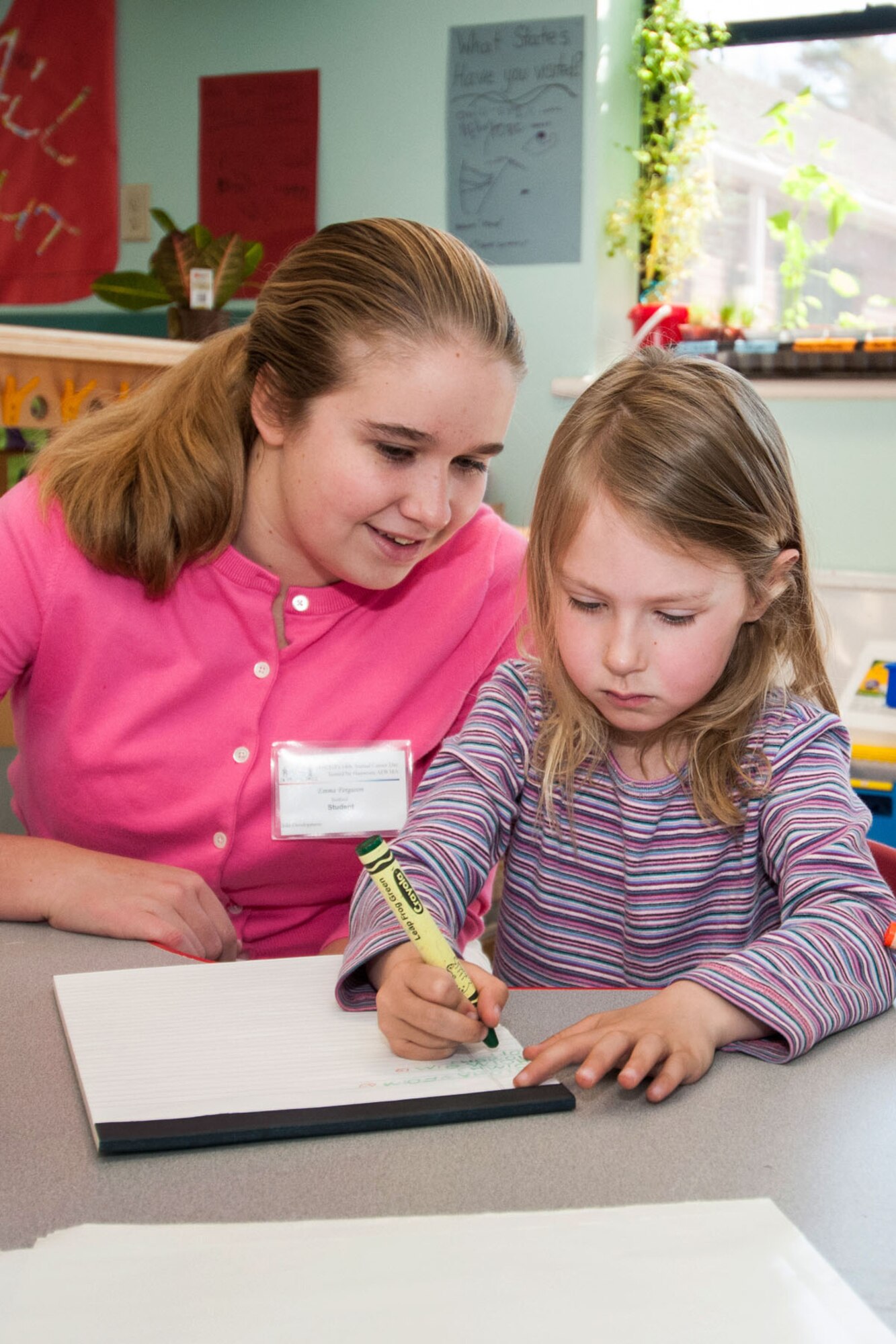 HANSCOM AIR FORCE BASE, Mass. -- Emma Ferguson, a student at Bedford High School, gets a first-hand look into being an early childhood provider during a career day event May 2. Ferguson watches Orin Lewis while she writes at the Child Development Center. The annual event is sponsored by the Lexington-Concord Chapter of the Armed Forces Communications and Electronics Association Diversity Committee to learn about career opportunities available at Hanscom and across the Air Force. (U.S. Air Force photo by Rick Berry)