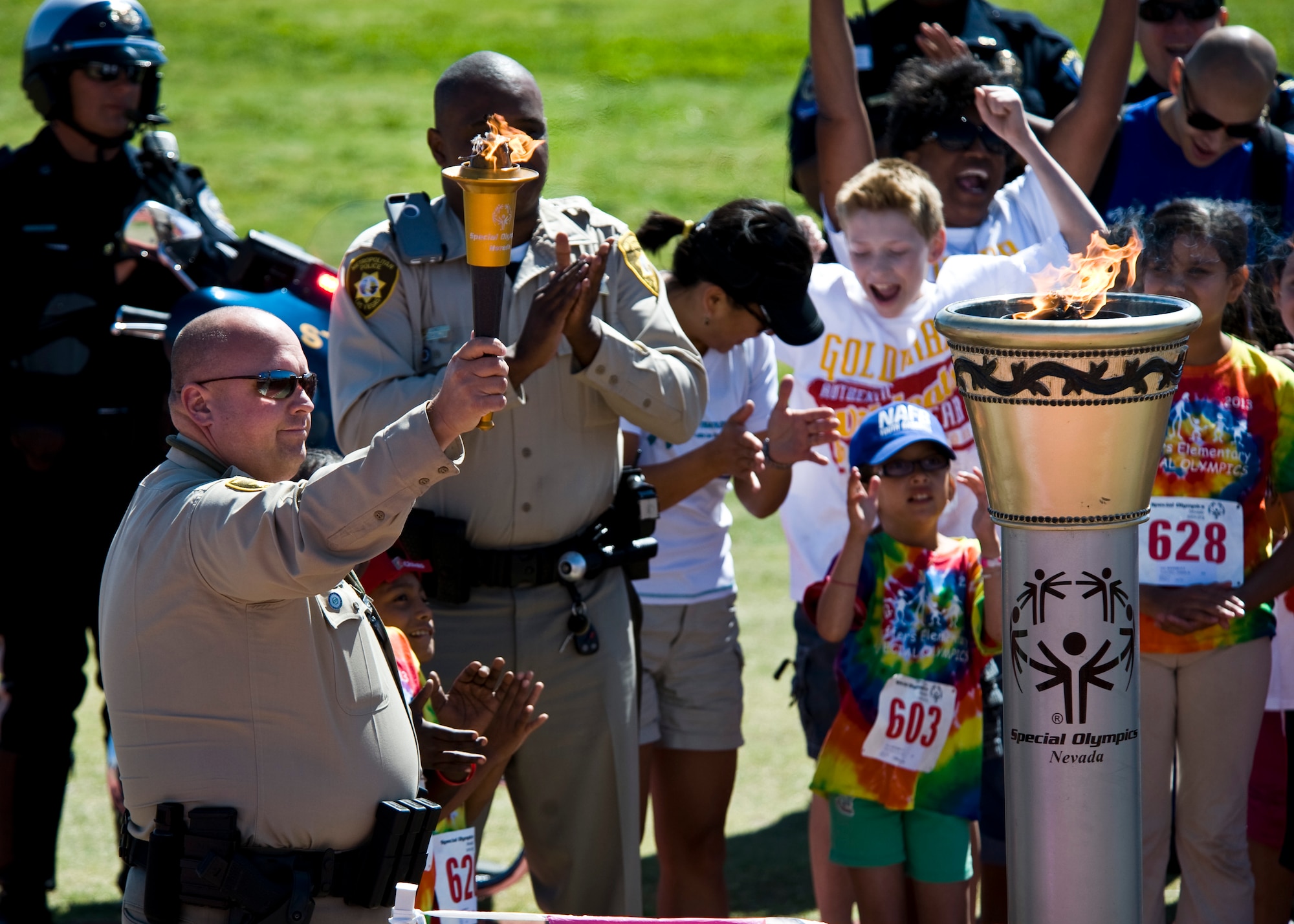 A Las Vegas Metropolitan Police Officer lights the torch during the opening ceremony of the 11th Annual Nevada Special Olympics May 2, 2013, at Cheyenne High School in North Las Vegas, Nev. The concept for Special Olympics was born in the early 1960s, when Eunice Kennedy Shriver started a day camp for people with intellectual disabilities at her home in Rockville, Md.  (U.S. Air Force Photo by Airman 1st Class Jason Couillard)