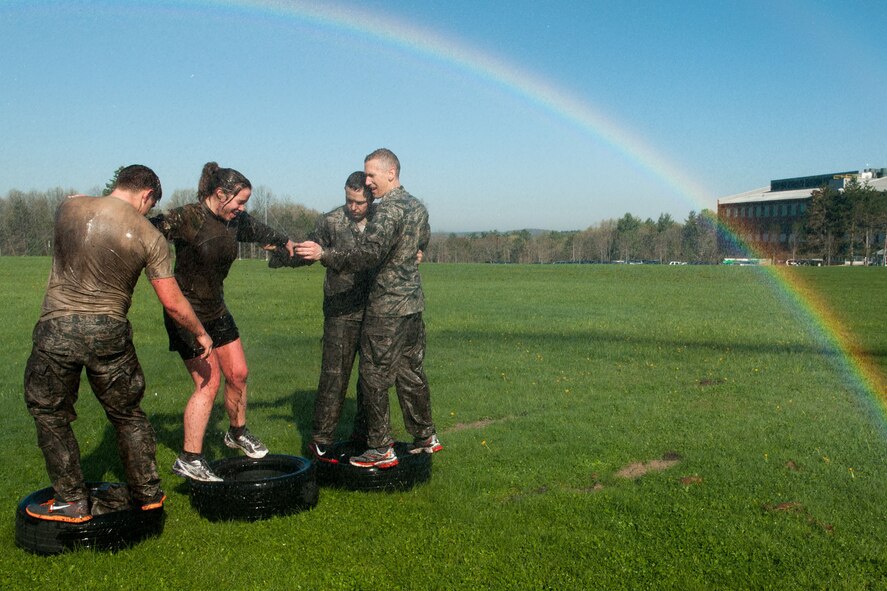 HANSCOM AIR FORCE BASE, Mass. -- (left to right) Second Lt. Joshua Wall, Capt. Mary Harvey, Col. William Polakowski and Capt Mike Brownlee maneuver through a tire obstacle as water showers over them during Warrior Day, May 1. Teams from the National Guard, Air Force and Marines competed against one another as part of the monthly event. (U.S. Air Force photo by Rick Berry)