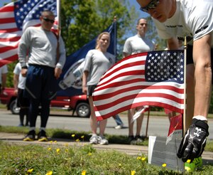 A Langley Airman plants an American flag in honor of a fallen Service member during the “Run for the Fallen” event in Hampton Roads, Va., May 2, 2013. Families of fallen Service members stood by their respective hero markers to thank the runners for their memorial run. (U.S. Air Force photo by Austin Harvill/Released)