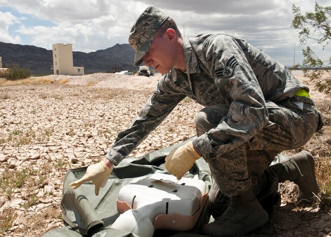 Senior Airman Travis Michel, 99th Force Support Squadron assignments counselor and casualty search and recovery team member, examines a simulated body part from a simulated victim of a C-17 Globemaster III crash for personal identifiable belongings May 6, 2013, during a Nellis Air Force Base, Nev., Casualty Search and Recovery Exercise. SAR teams are responsible for recovering human remains and identifying wreckage from crash sites to help with mishap investigations. (U.S. Air Force photo by Staff Sgt. Michael Charles)