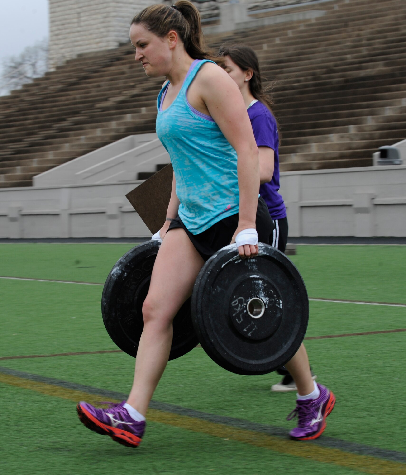 Staff Sgt. Samantha Scott, 509th Bomb Wing Command Post training manager, race with 25-pound plates across a football field during the K-State CrossFit Challenge in Manhattan, Kan., April 27, 2013.  After dropping the weights, the participants ran the bleachers eight times, doing burpees between each set. (U.S. Air Force photo by Staff Sgt. Alexandra M. Boutte/Released)