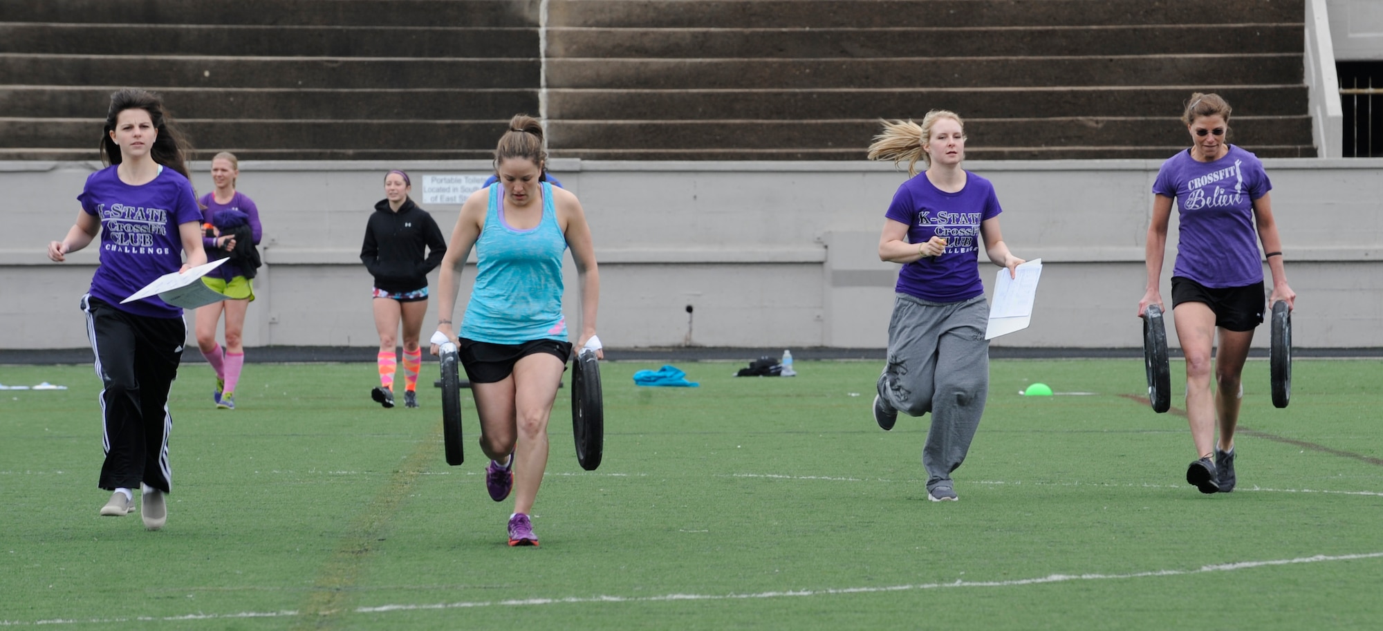 Staff Sgt. Samantha Scott, 509th Bomb Wing Command Post training manager, and her teammate race with 25-pound plates across a football field during the K-State CrossFit Challenge in Manhattan, Kan., April 27, 2013.  After dropping the weights, the participants ran the bleachers eight times, doing burpees between each set. (U.S. Air Force photo by Staff Sgt. Alexandra M. Boutte/Released)