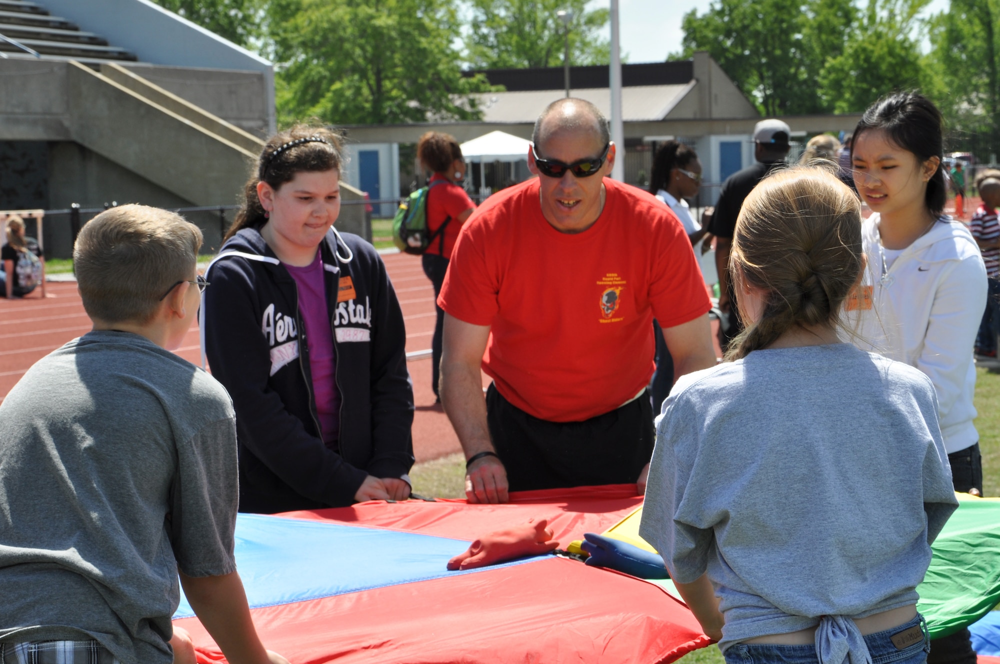Spc. Jeffrey Arnold, center, instructs children on how to make “pigs fly” during the George Green 42nd Annual Special Education Field Day, April 2, 2013 at John B. Todd Stadium in Newport News, Va. Arnold helped the children shoot toy pigs into the air using a parachute as one of the more than 35 events school children could participate in at the field day. (U.S. Air Force photo by Tech. Sgt. April Wickes/Released)