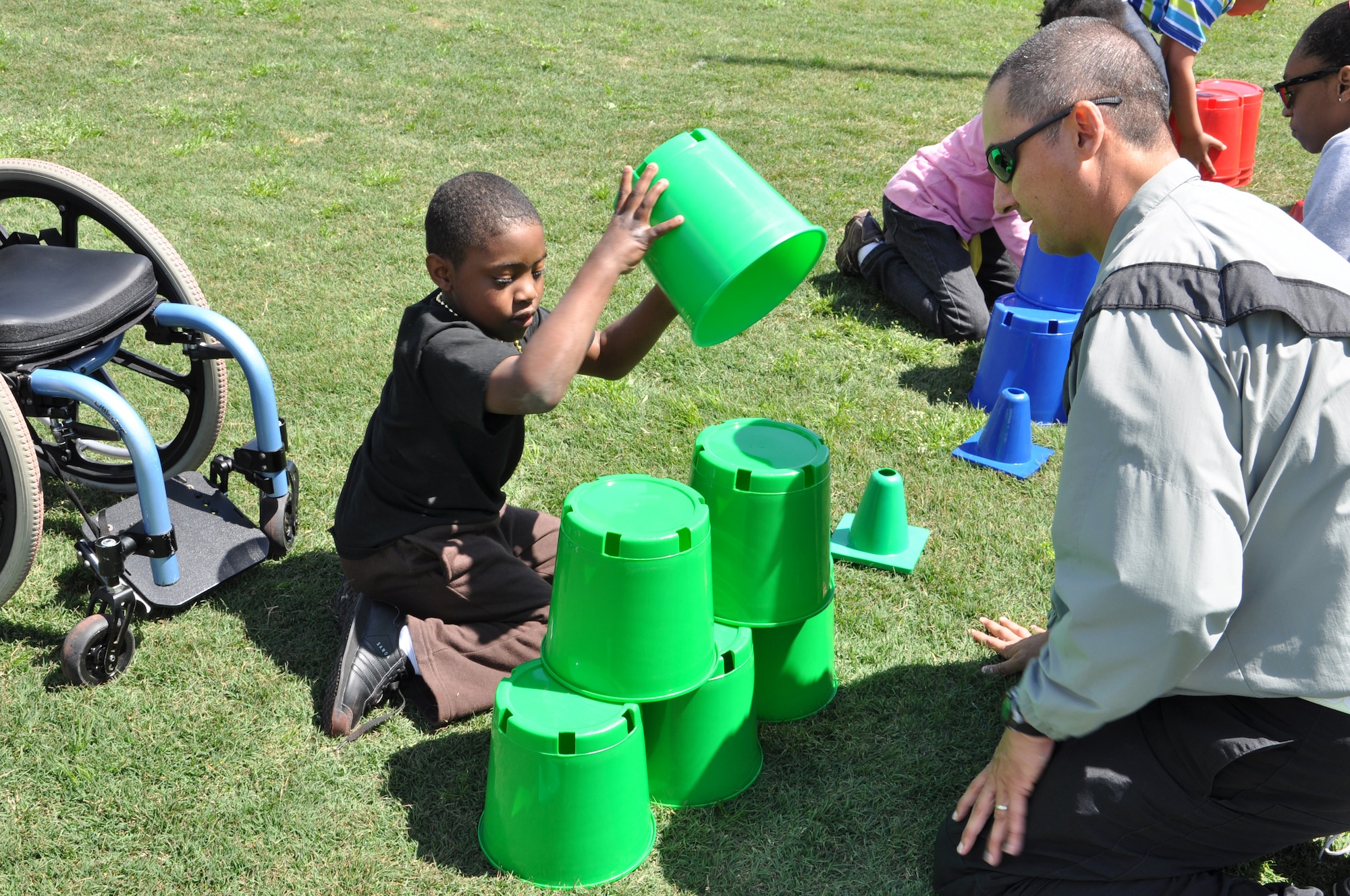 Staff Sgt. Thomas Adams with the 689th Rapid Port Opening Element, helps a child with the cup stacking event during the George Green 42nd Annual Special Education Field Day, April 2, 2013 at John B. Todd Stadium in Newport News, Va. Soldiers from the 689th and 690th Rapid Port Opening Elements helped children participate in more than 35 events, such as corn hole, flying disc, cup stacking, giant-ball rolling, and relay races. (U.S. Air Force photo by Tech. Sgt. April Wickes/Released)