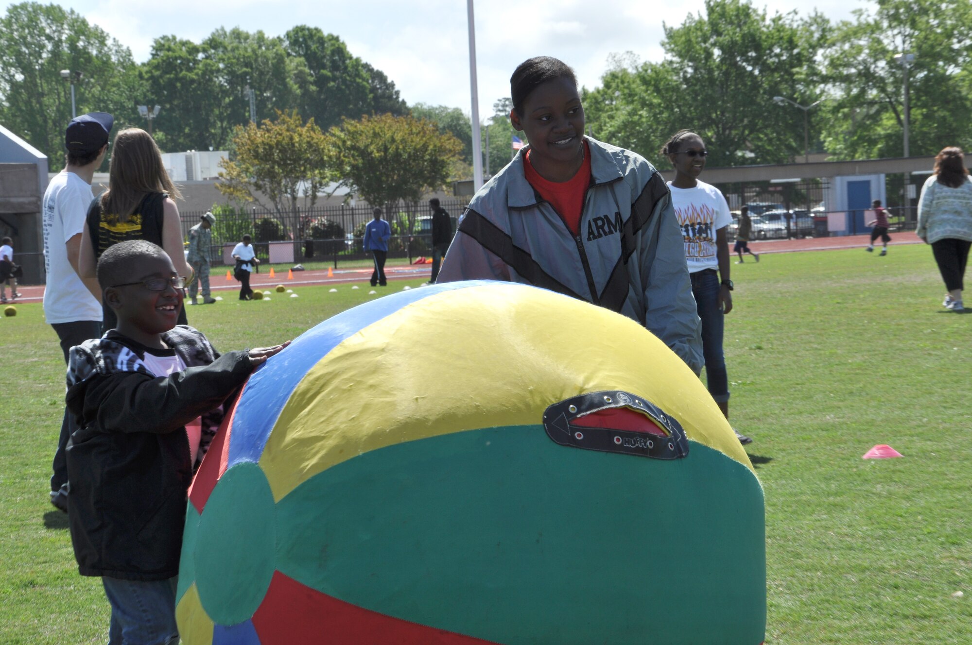 Spc. Angelica Moses-Berry with the 689th Rapid Port Opening Element, helps a child roll a giant beach ball between two cones during the George Green 42nd Annual Special Education Field Day, April 2, 2013 at John B. Todd Stadium in Newport News, Va. Moses-Berry was one of more than 40 Army Soldiers that volunteered to help with the even that was attended by 700 school children. (U.S. Air Force photo by Tech. Sgt. April Wickes/Released)