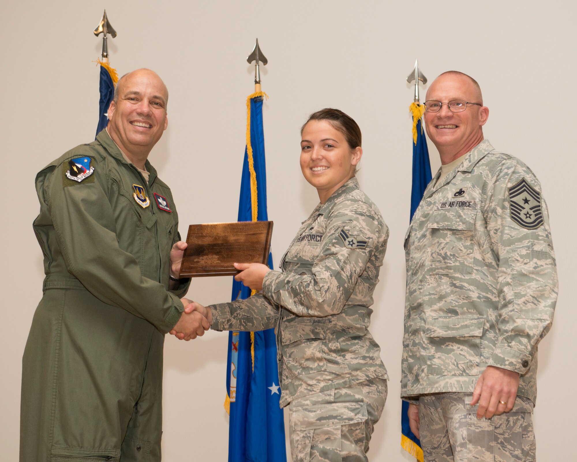 Airman 1st Class Stephanie L. Grebe, 412th Security Forces Squadron (center), receives the 412th Test Wing's Airman of the Quarter Award from Brig. Gen. Michael T. Brewer, 412th TW commander; as 412th TW Command Chief Master Sgt. Brian Randolph looks on. (U.S. Air Force photo by Edward Cannon)
