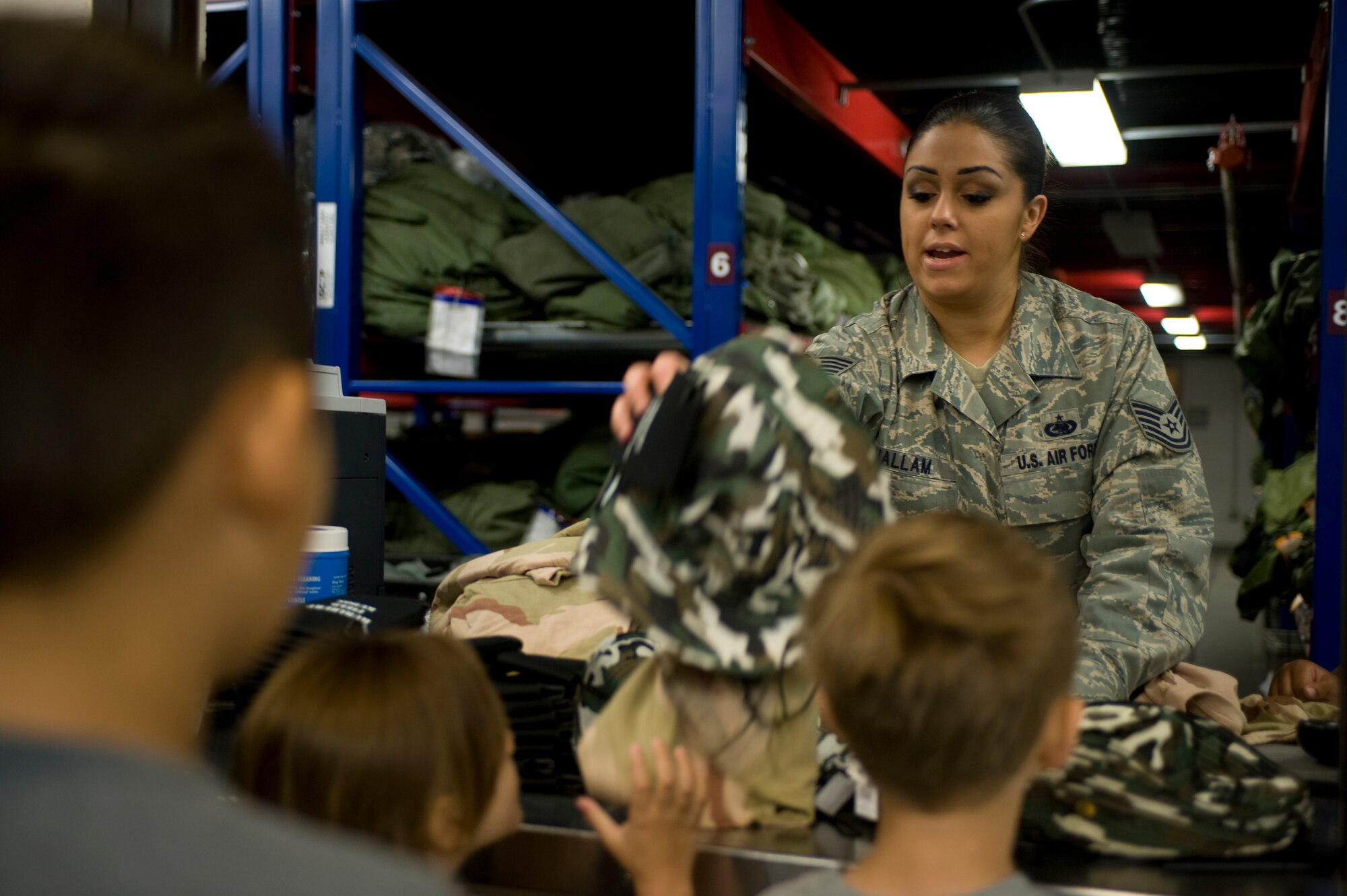 Children await a bag of goods from Tech. Sgt. Gina Hallam, NCOIC of individual protective equipment at the 1st Special Operations Logistics Readiness Squadron, at the Kids Understand Deployment Operations event at the Deployment Control Center auditorium on Hurlburt Field, Fla., April 27, 2013.  This station provided the first of a long list of activities that imitate pre-deployment processes, where Airmen are issued various items necessary for deployment.  (U.S. Air Force photo by Airman 1st Class Hayden K. Hyatt) 