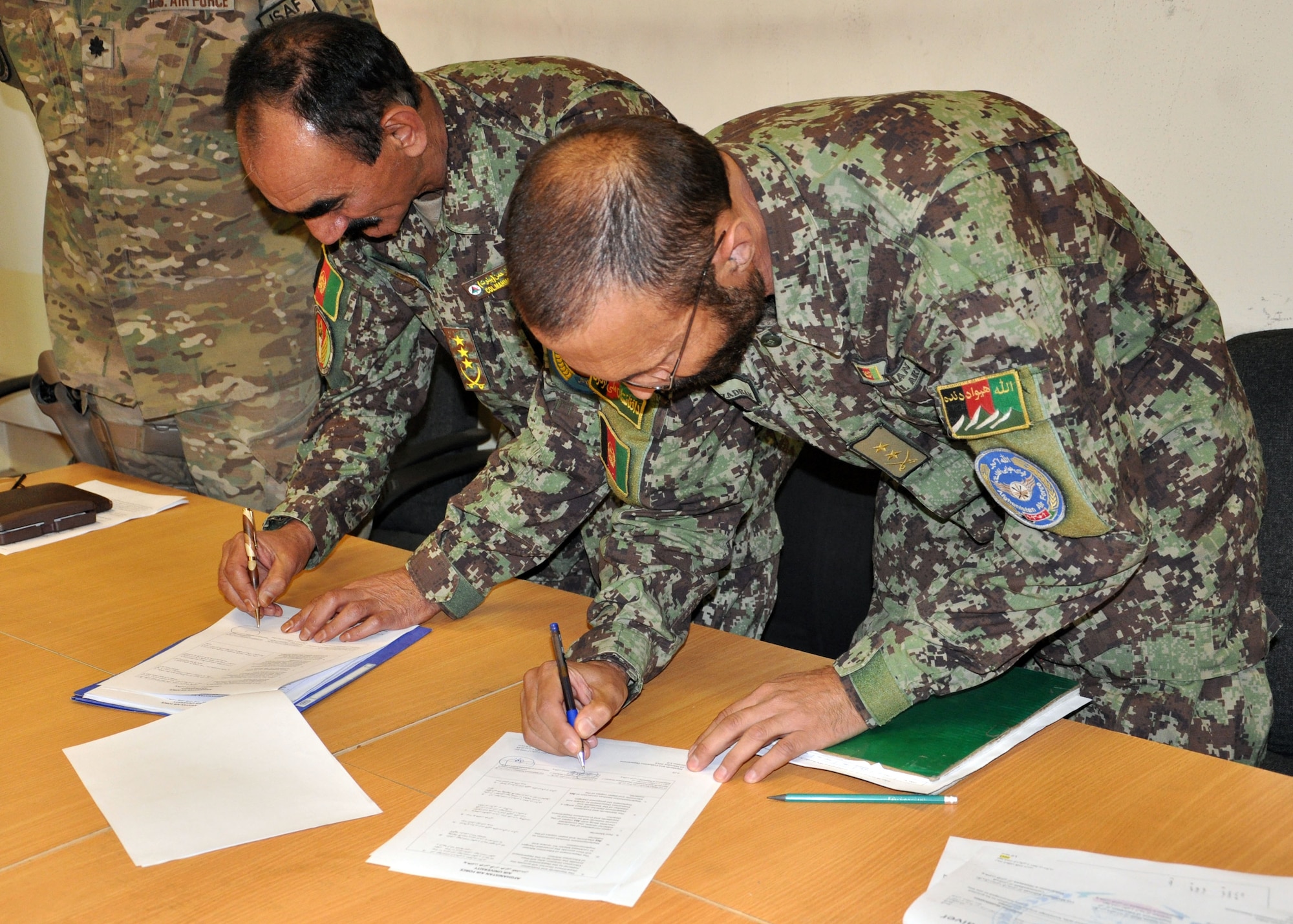 Afghan Air Force Col. Mahmood Rahman, Commandant of Pohantoon-e-Hawayee “Air University”, and Lt. Col. Raees Khan, PeH education planning officer, sign six new training decrees in a ceremony May 4, 2013 at Kabul International Airport, Afghanistan. The implementation of these decrees marks the first time in the school’s history to have standard operating procedures for the teaching of the students. (U.S. Air Force photo/Capt. Anastasia Wasem)
