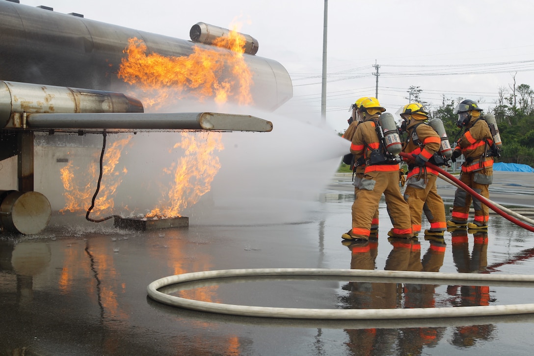 Firefighters battle a fire during a mobile aircraft fire training device exercise at the Camp Hansen Joint Training Facility May 2. Firefighters used the device to create controlled burns in a replicated fuselage. The flames, coupled with smoke machines and audio devices, create realistic training conditions for the firefighters. The firefighters are with Marine Corps Installation Pacific Fire and Emergency Services. Photo by Lance Cpl. Henry J. Antenor
