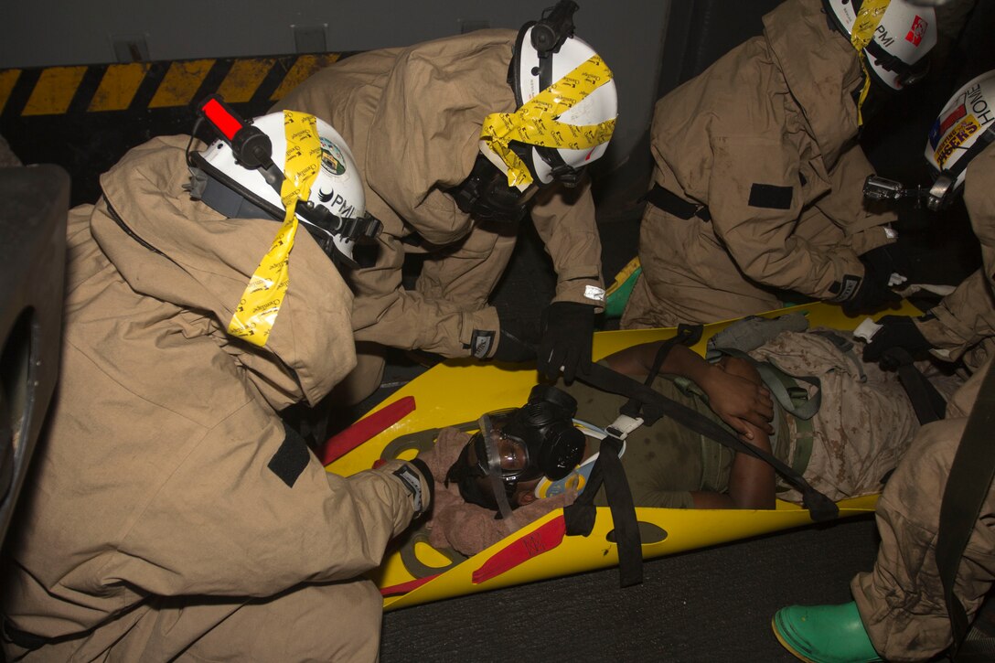 Chemical, biological, radiological and nuclear defense specialist U.S. Marines assigned to the 26th Marine Expeditionary Unit (MEU), strap a simulated casualty into a Skedco during a confined space search and rescue in a hazardous environment exercise, in the hangar bay of the USS Kearsarge (LHD 3), while underway, May 8, 2013. The 26th MEU is deployed to the 5th Fleet area of operations aboard the Kearsarge Amphibious Ready Group. The 26th MEU operates continuously across the globe, providing the president and unified combatant commanders with a forward-deployed, sea-based quick reaction force. The MEU is a Marine Air-Ground Task Force capable of conducting amphibious operations, crisis response and limited contingency operations. (U.S. Marine Corps photograph by Cpl. Kyle N. Runnels/Released)