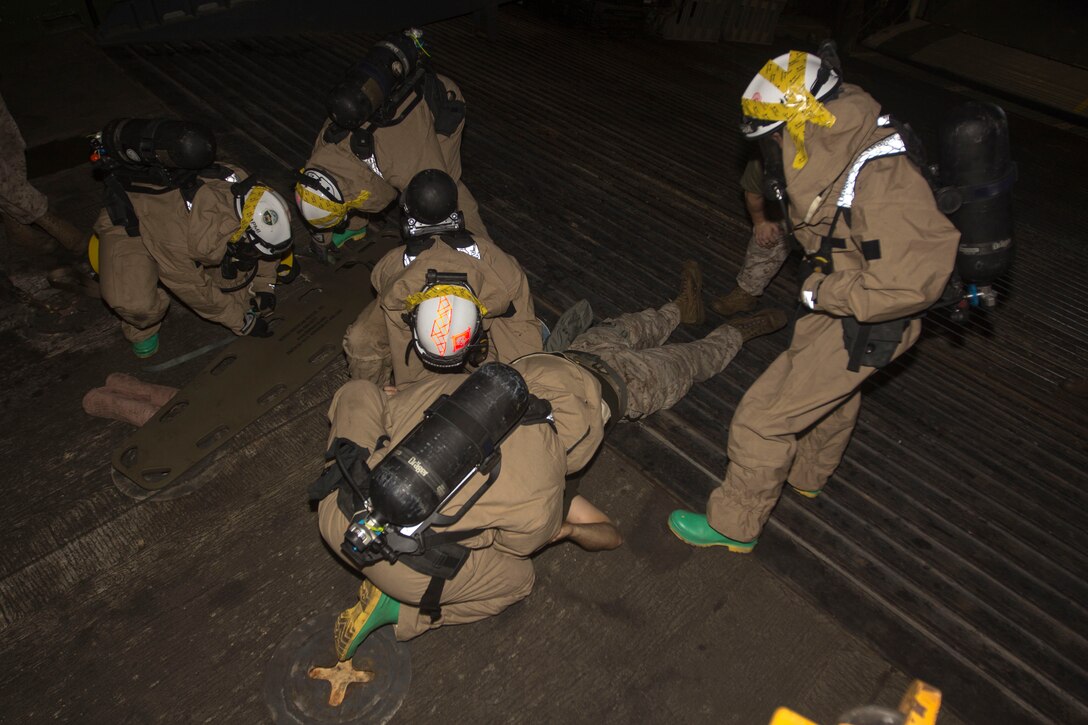 Chemical, biological, radiological and nuclear defense specialist U.S. Marines assigned to the 26th Marine Expeditionary Unit (MEU), strap an M-50 field protective mask to a simulated casualty and prepare a stretcher during a confined space search and rescue in a hazardous environment exercise, in the hangar bay of the USS Kearsarge (LHD 3), while underway, May 8, 2013. The 26th MEU is deployed to the 5th Fleet area of operations aboard the Kearsarge Amphibious Ready Group. The 26th MEU operates continuously across the globe, providing the president and unified combatant commanders with a forward-deployed, sea-based quick reaction force. The MEU is a Marine Air-Ground Task Force capable of conducting amphibious operations, crisis response and limited contingency operations. (U.S. Marine Corps photograph by Cpl. Kyle N. Runnels/Released)